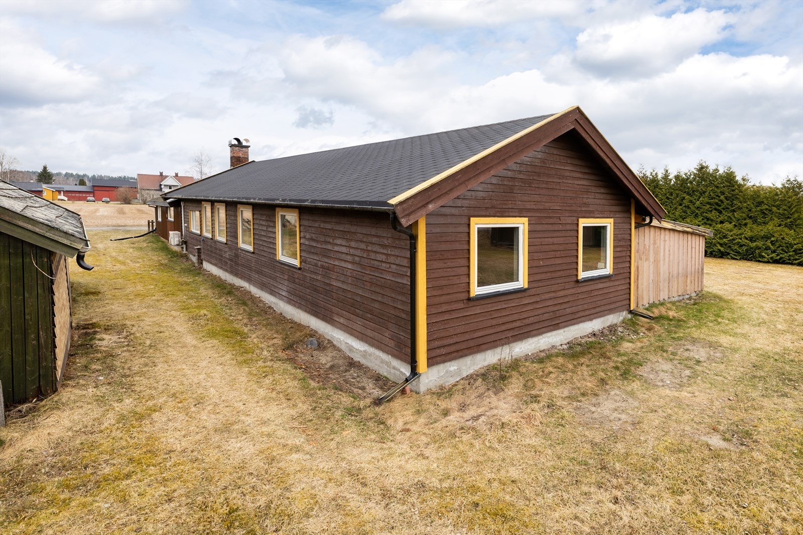 Fasaden er kledd med en kombinasjon av liggende og stående trekledning. Takvann ledes ut på terreng via takrenner i metall. Galleribilde