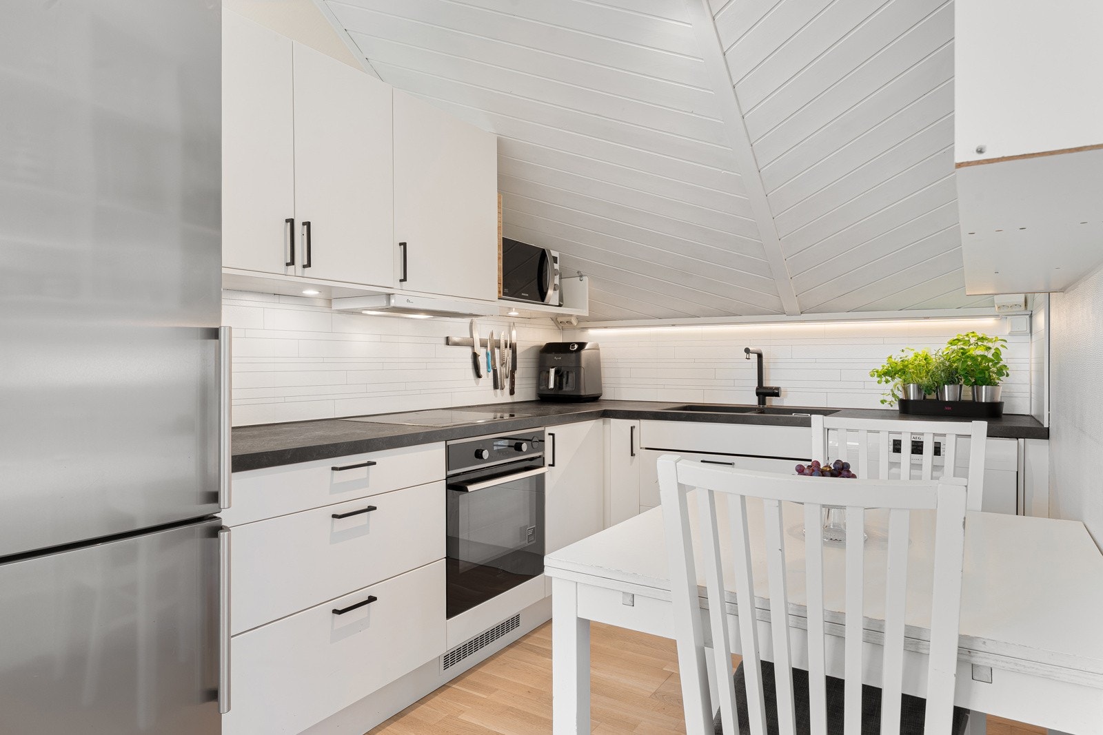 Kjøkkenet er praktisk utformet og er utstyrt med integrerte hvitevarer, deriblant oppvaskmaskin, stekeovn og induksjonstopp, i tillegg til frittstående kjøl- og fryseskap.