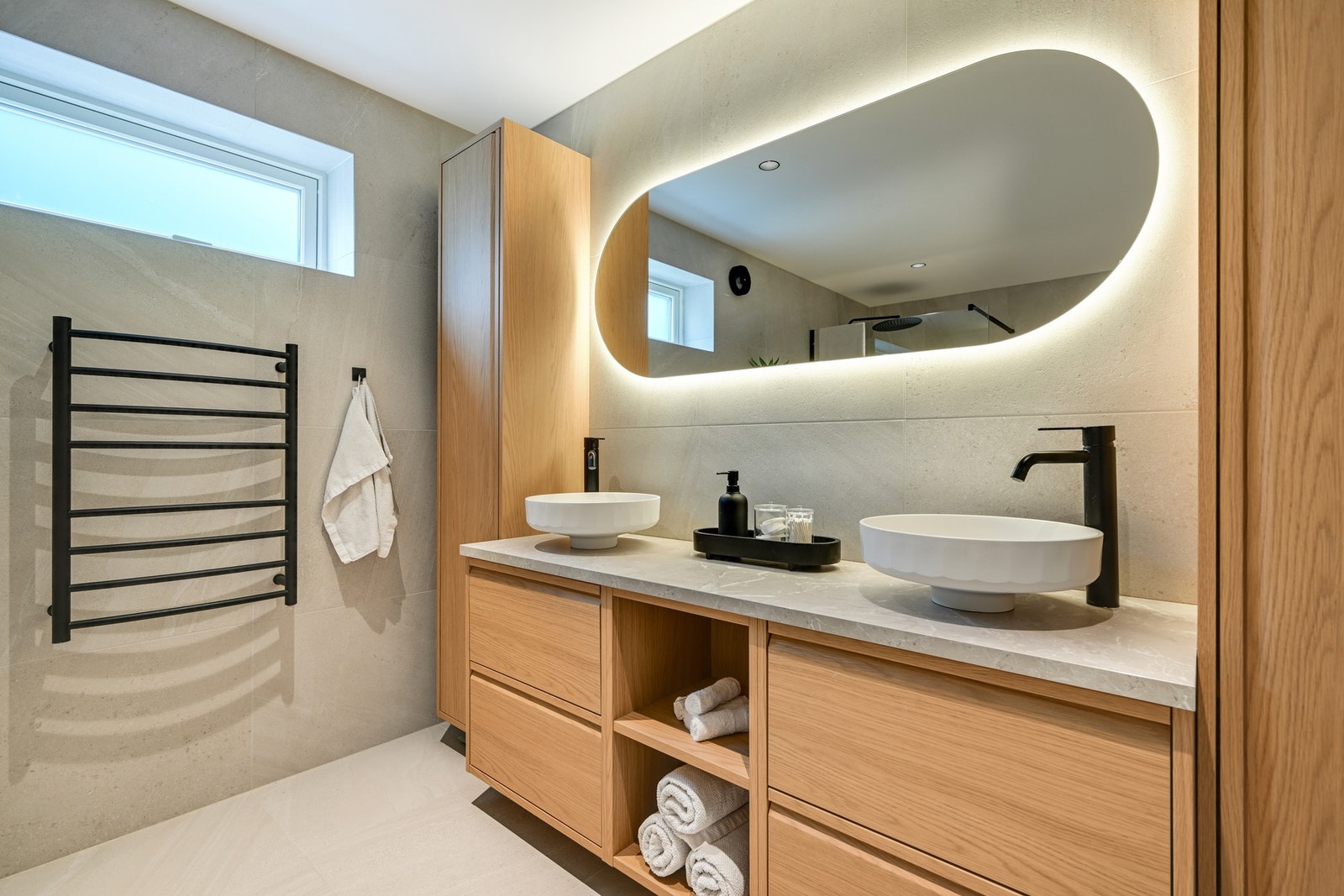 Den doble servantløsningen med lekker innredning, toppmonterte servanter og elegant bakbelyst speil gir rommet et moderne preg. Galleribilde