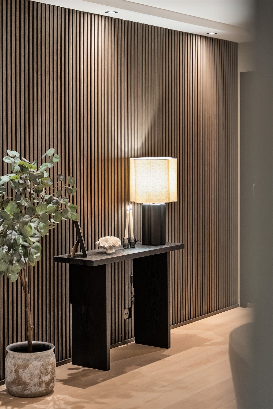 Spileveggen, belyst av downlights. Et gjennomgående designgrep som gir leiligheten karakter. Galleribilde