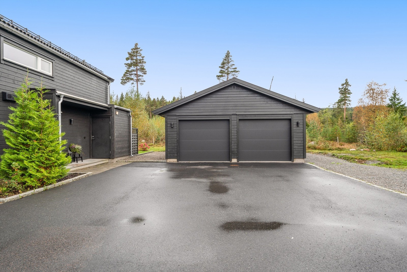 Dobbeltgarasje som deles med nabo. Gjesteparkering på grusplass til høyre. Galleribilde