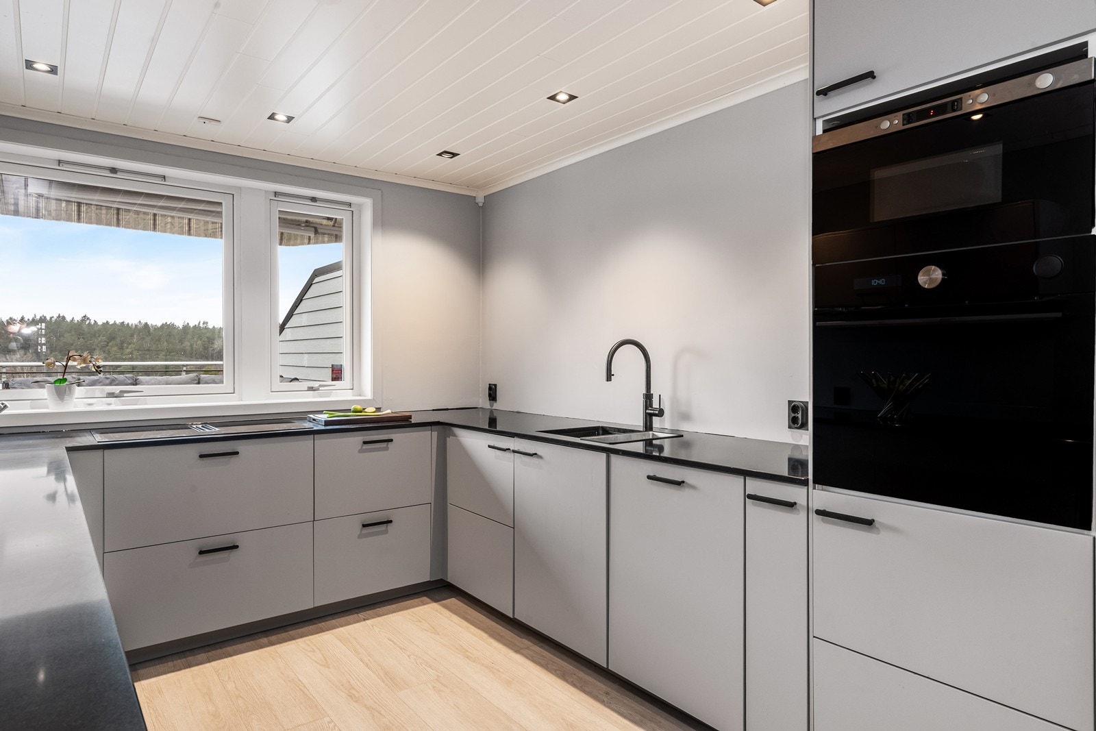 Kjøkkeninnredning med slette fronter, benkeplate i stein og integrerte hvitevarer. Galleribilde