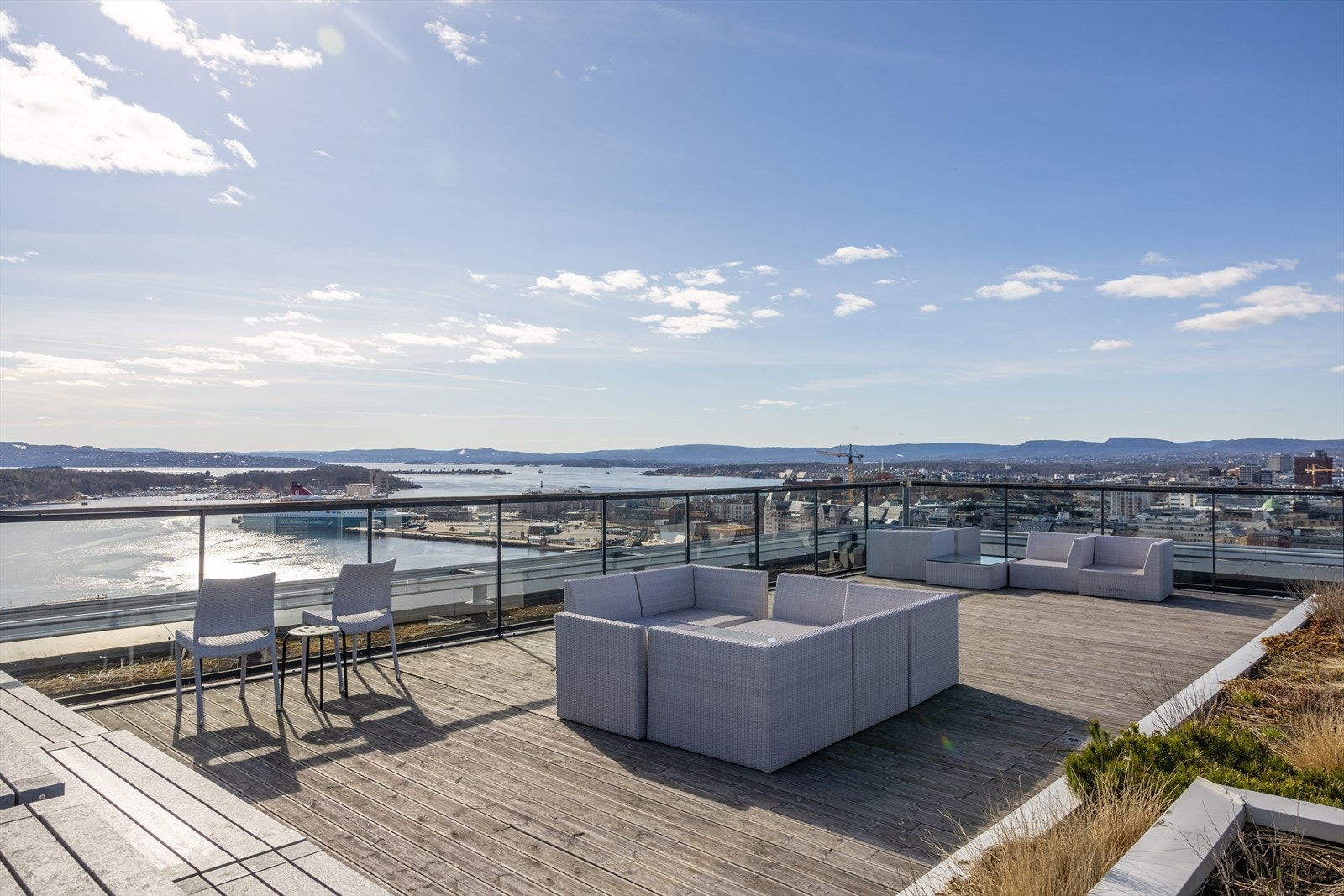 Solrik takterrasse med flere sitteområder og fantastisk utsyn mot sjø og horisont Galleribilde