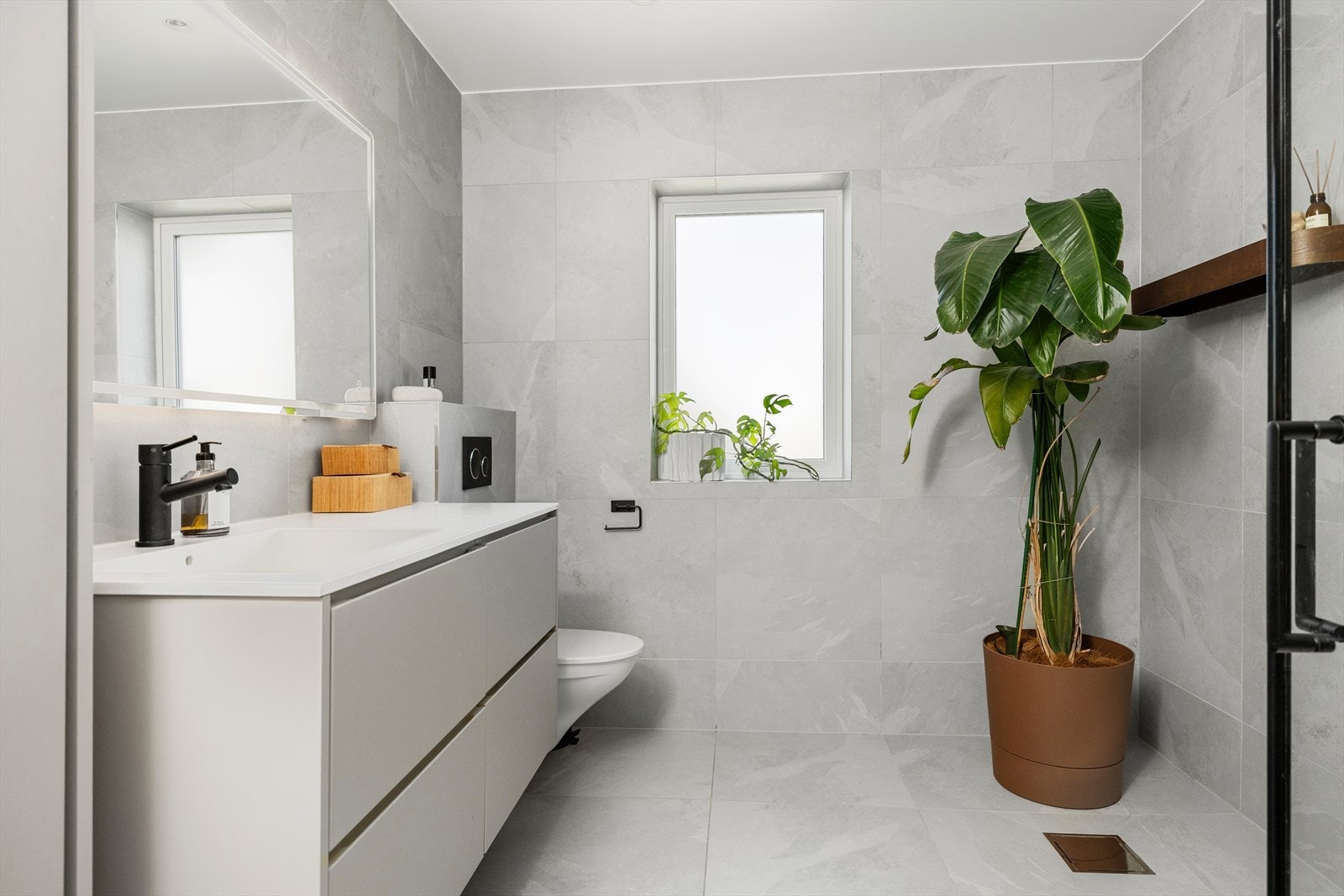Badet er i en moderne utførelse med store fliser, varmekabler i gulvet og med muligheter for badekar om ønskelig. Galleribilde