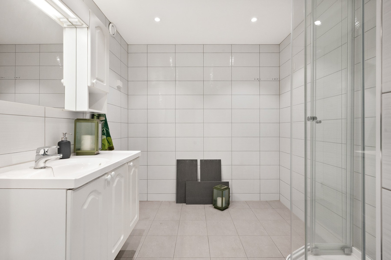 Flislagt bad med elektriske varmekabler i gulv. Badet er innredet med baderomsinnredning med nedfelt servant, speilskap med belysning, dusjkabinett samt opplegg for vaskemaskin Galleribilde
