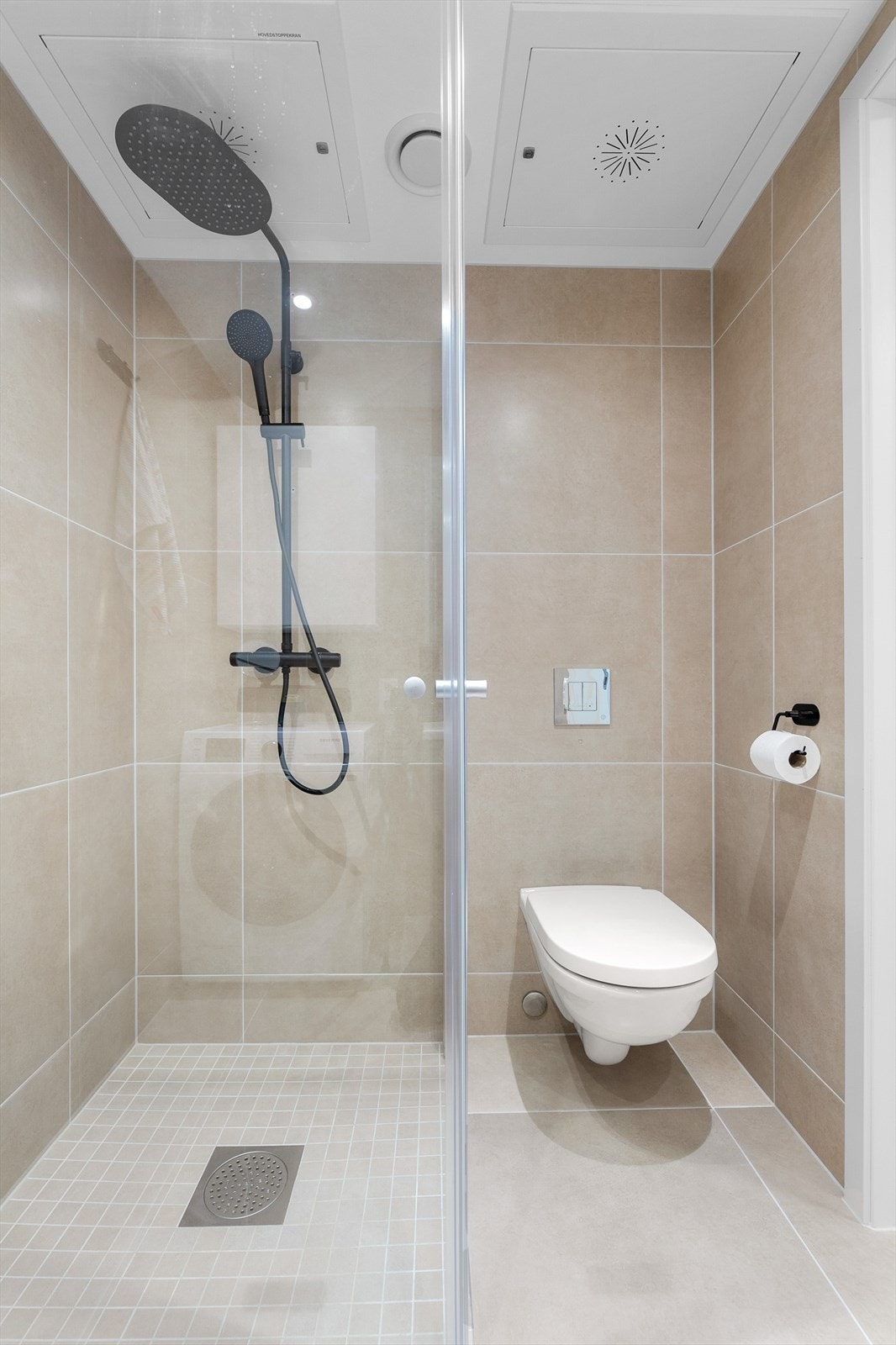Badet er utstyrt med vegghengt toalett og dusjhjørne med innfellbare glassdører. Galleribilde