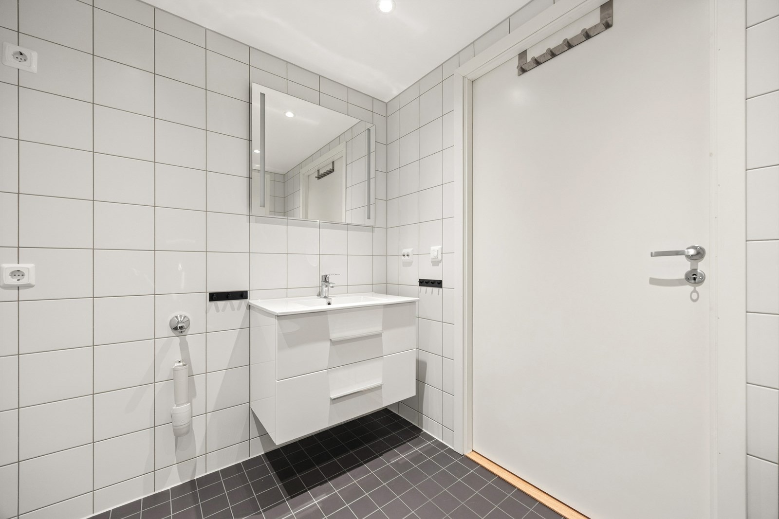 Klassisk bad med lyse overflater og et stilrent uttrykk. Det er opplegg for vaskemaskin på badet. Galleribilde