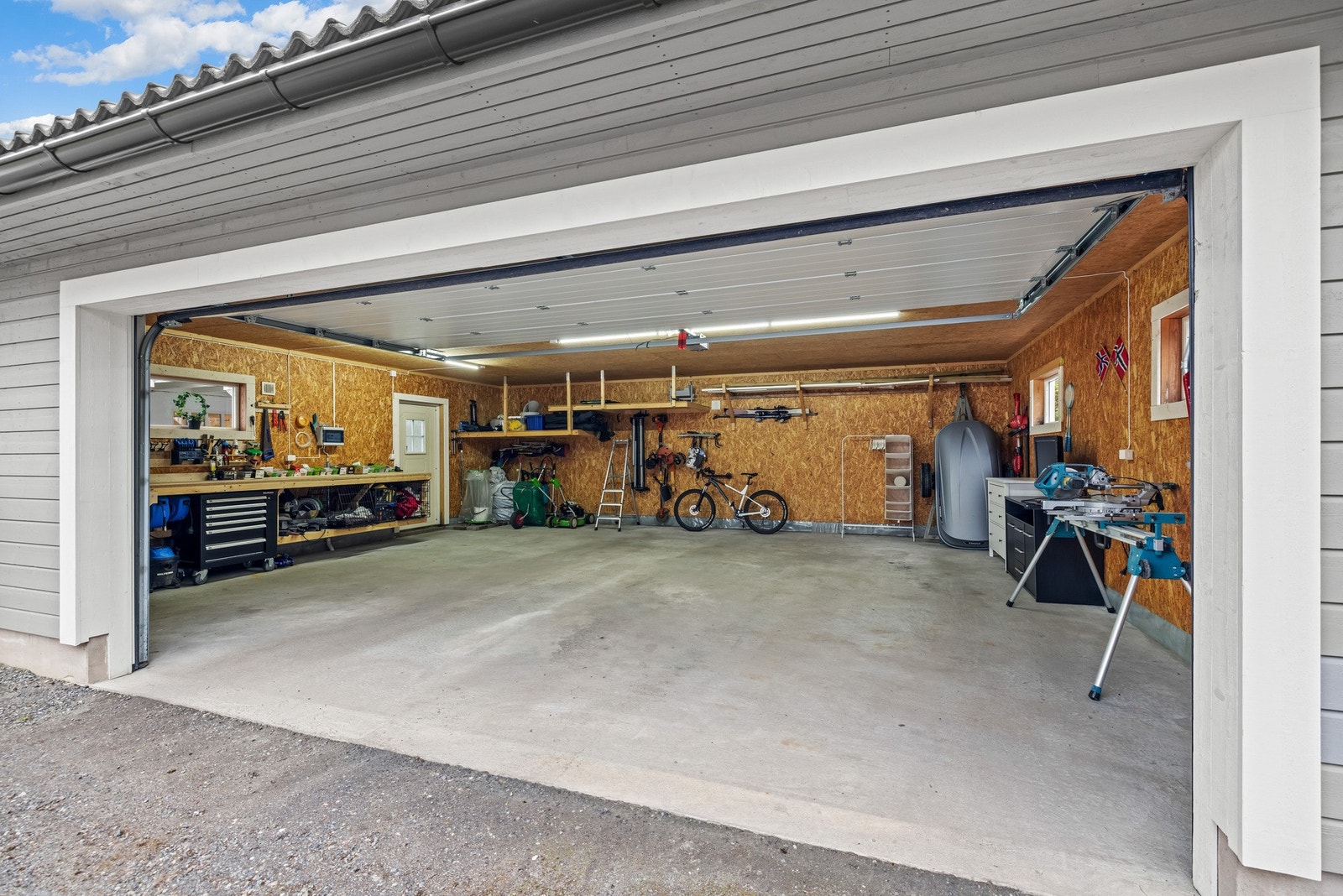 Stor dobbelgarasje på ca. 62 m² innredet med arbeidsbenk, god belysning og flere smarte oppbevaringsløsninger. Galleribilde