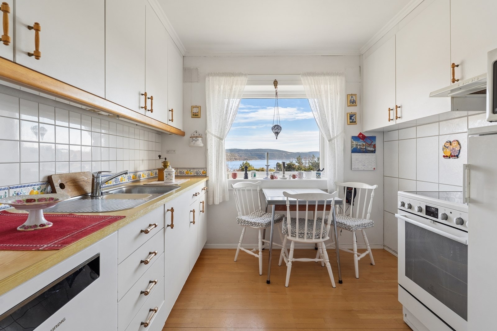 Kjøkken med spiseplass og flott utsikt. Innredningen har glatte fronter og benkeplate i laminat. Galleribilde