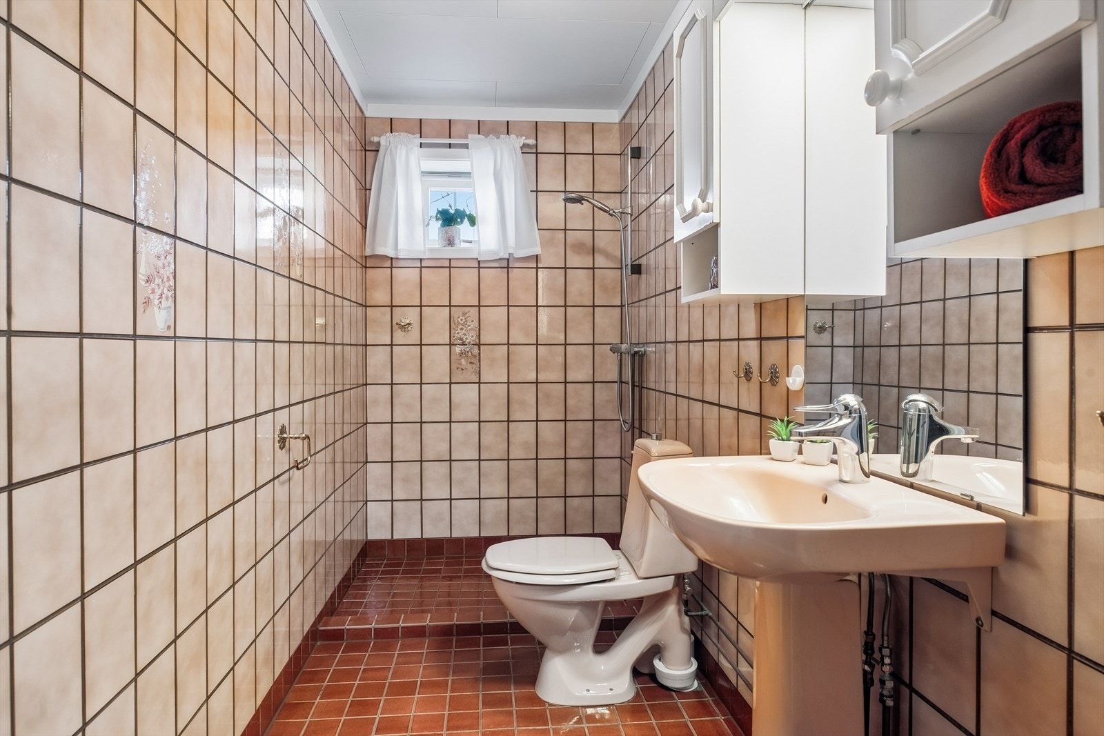 Badet i underetasjen er fra byggeåret, med flislagt gulv med varmekabler og flislagte vegger. Galleribilde