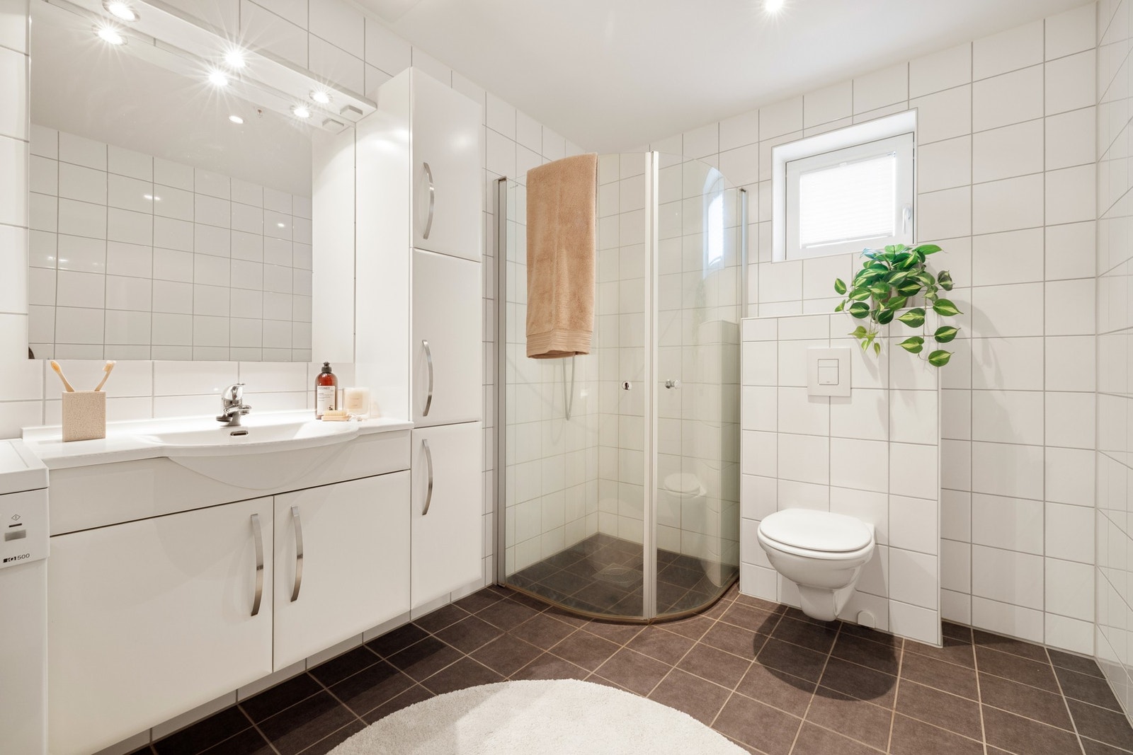 Badet er på 6,4 kvm og er helfliset med lyse og tidløse fliser på veggene, og mørke fliser på gulvet. Galleribilde