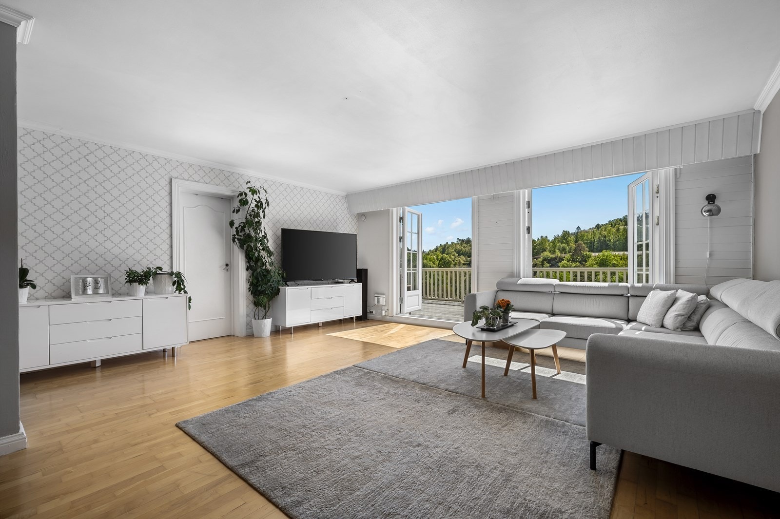 Stuen er romslig og luftig, og har to store dobbeltdører som åpner opp mot en sørvendt veranda. Galleribilde