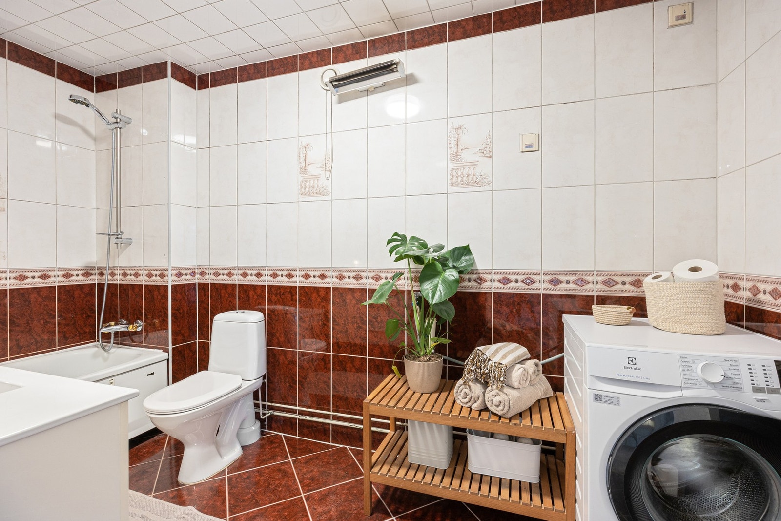 Badet er videre utstyrt med badekar med dusjforheng, gulvstående toalett og opplegg for vaskemaskin. Galleribilde