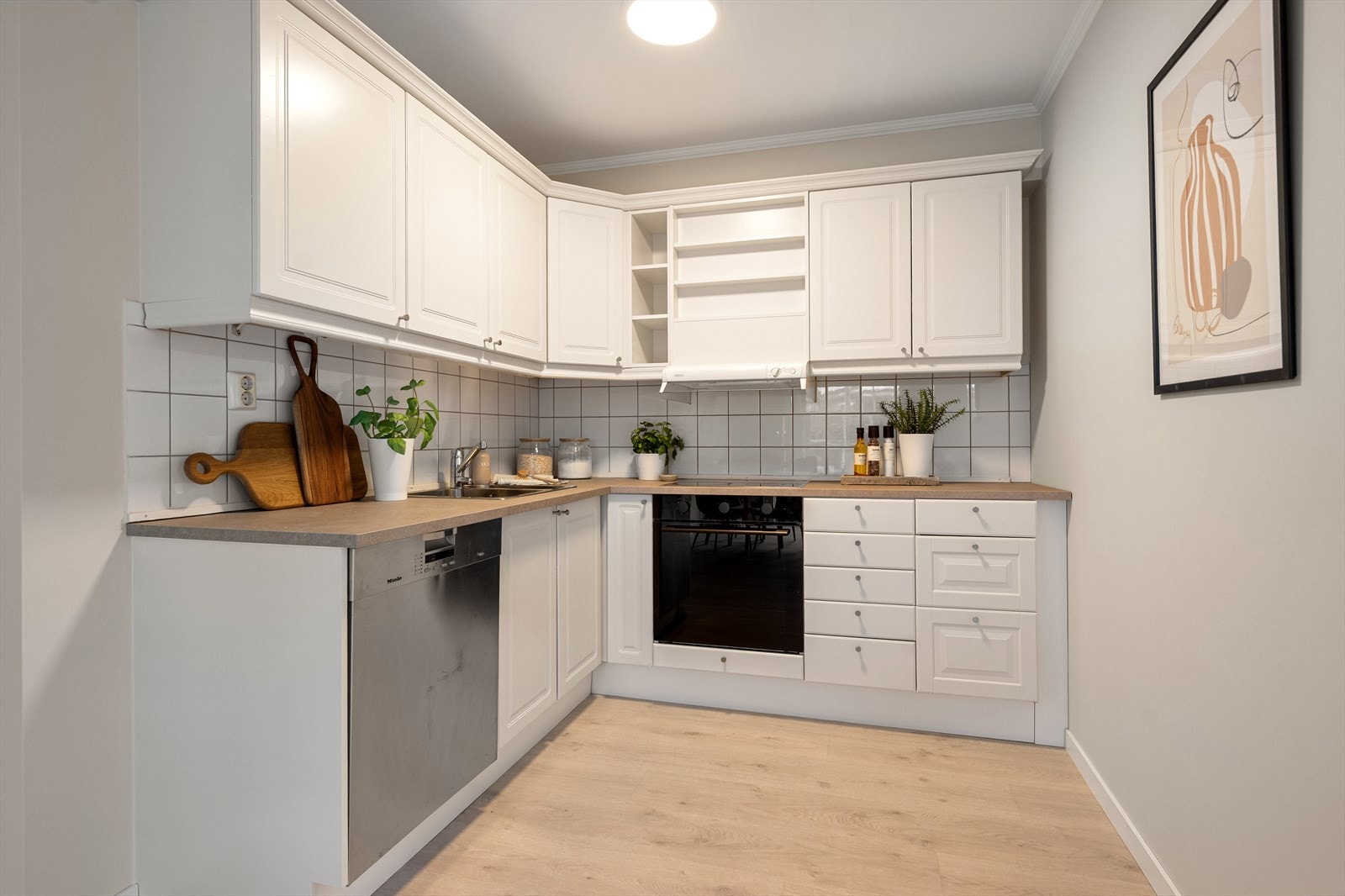 Innredningen er trolig fra byggeår, med profilerte fronter malt i en hvit tone. Benkeplaten er i laminat, med nedfelt og overlimt oppvaskkum i rustfritt stål og ettgreps kjøkkenbatteri i krom. Galleribilde