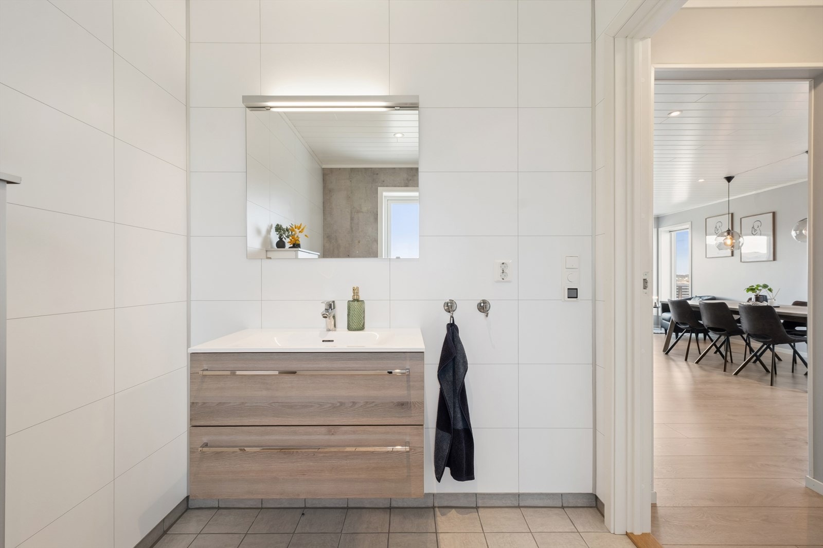 Også dette badet har flislagt gulv med gulvvarme, vegghengt toalett og baderomsinnredning med heldekkende servant. Galleribilde