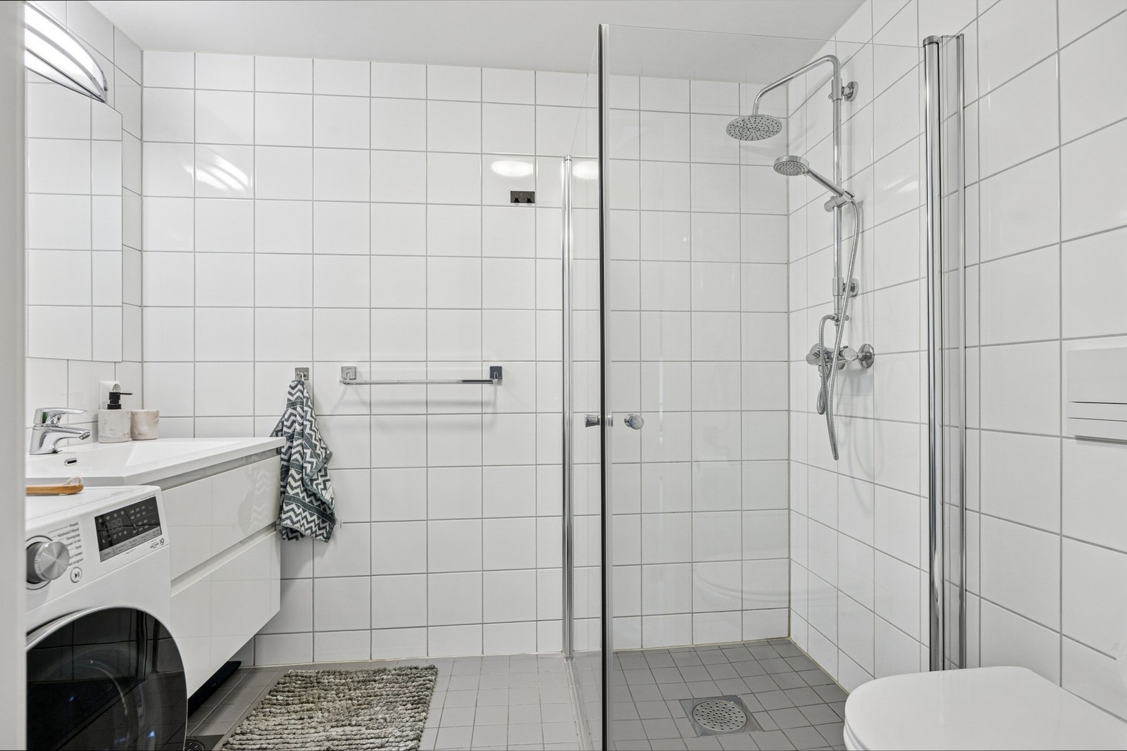 Badet er på ca. 4 kvm og fremstår som arealeffektivt og delikat, med fliser på vegger og gulv. Galleribilde