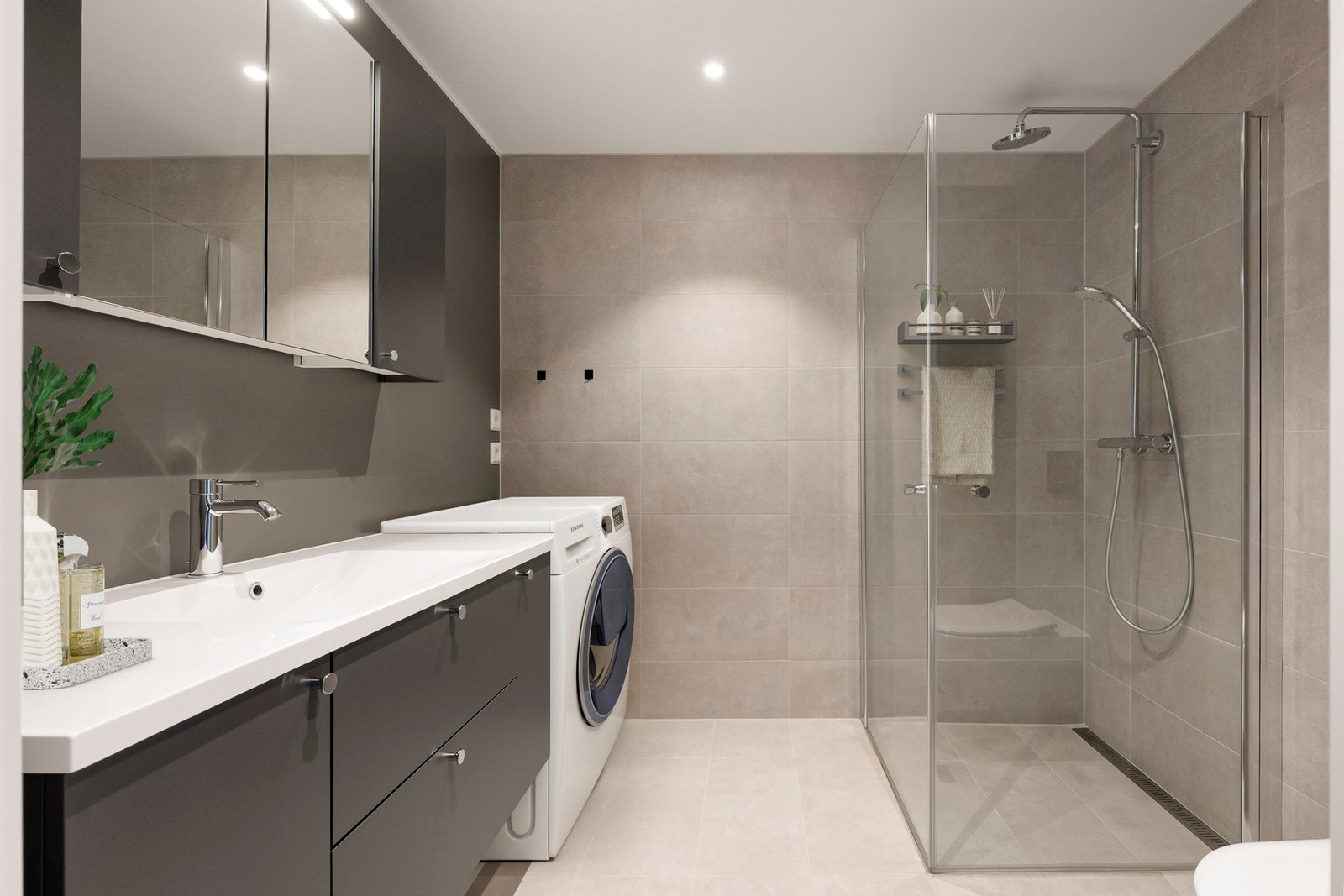 Badet har moderne overflater og materialer. Det er opplegg for vaskemaskin og tørketrommel. Bildet er digitalt stylet. Galleribilde