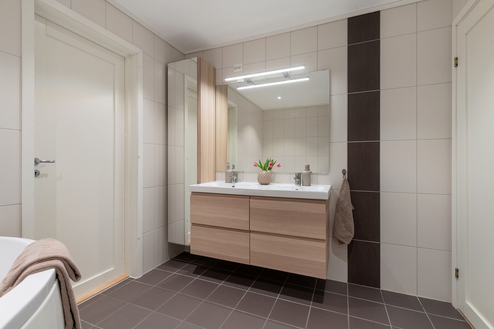 Badet har en dobbel, ovenpåliggende servant med vegghengt innredning og høyskap for ekstra oppbevaring. Galleribilde