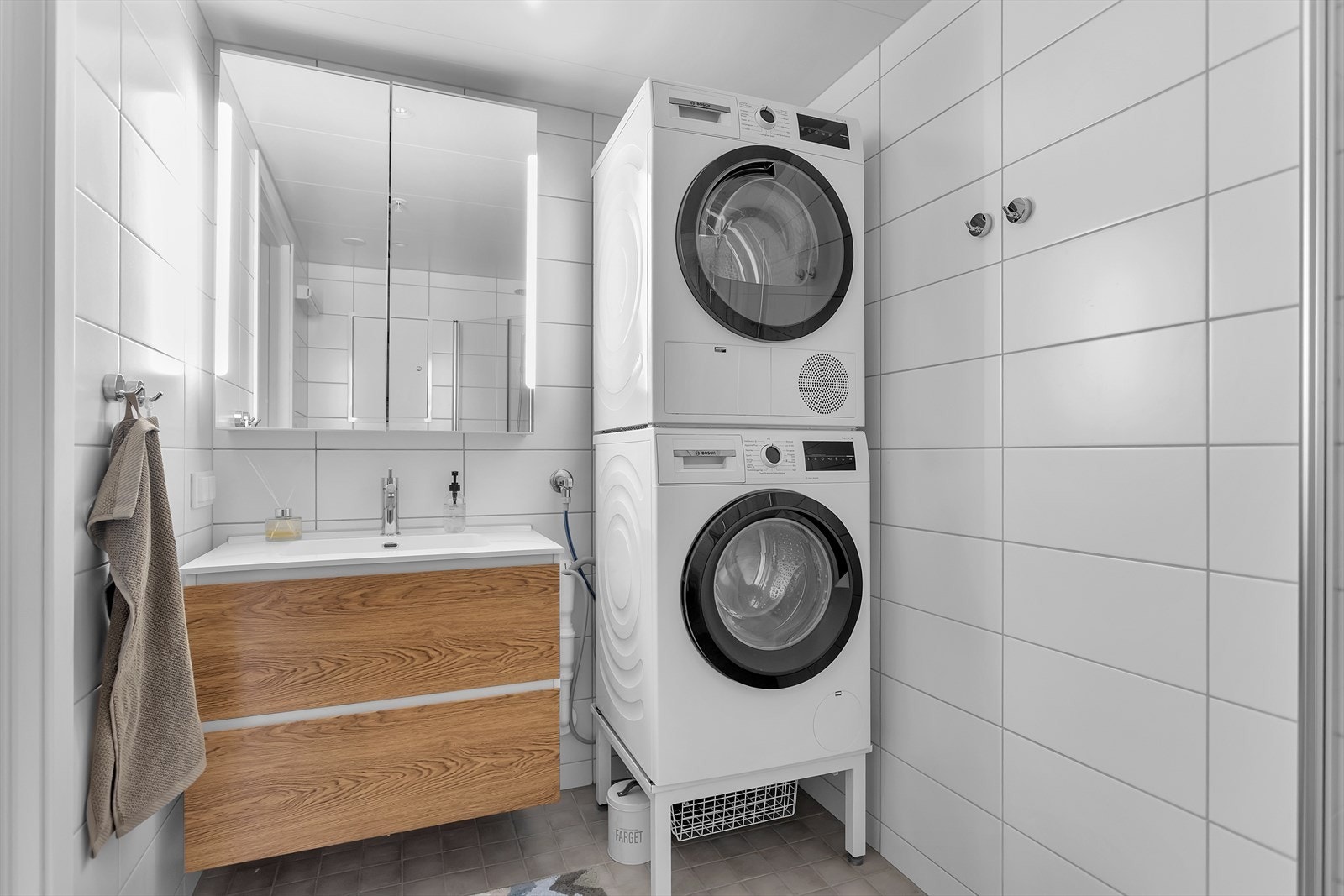 Videre finner du et speil med integrert belysning, en servant med praktiske underskuffer, vegghengt toalett samt opplegg for både vaskemaskin og tørketrommel. Badet har mekanisk avtrekk og vannbåren gulvvarme for ekstra komfort. Galleribilde