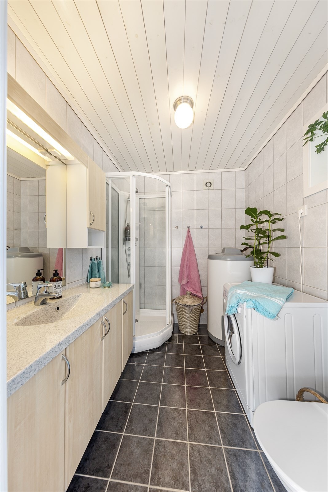 Badet er flislagt på vegger og gulv med varmekabler. Her er det rikelig med skapplass, toalett og dusjkabinett, varmtvannstanken samt opplegg for vaskemaskin Galleribilde
