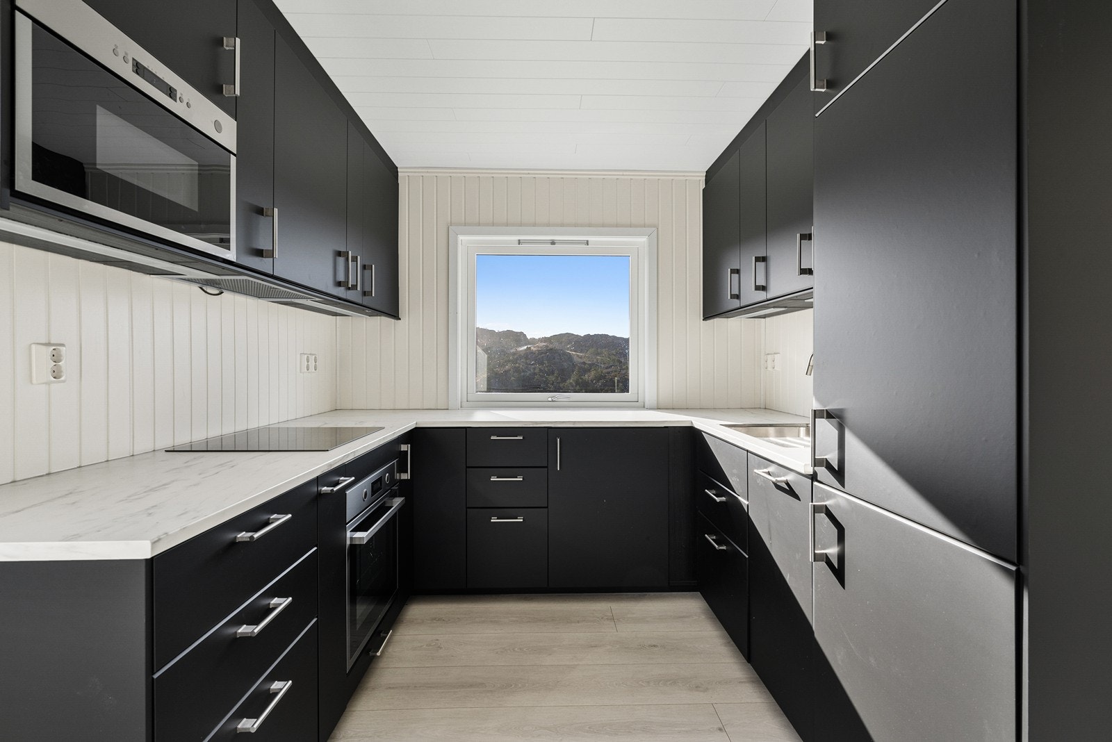 Kjøkkenet er fra Ikea og har innredning med svarte glatte fronter og benkeplate av laminat. Galleribilde