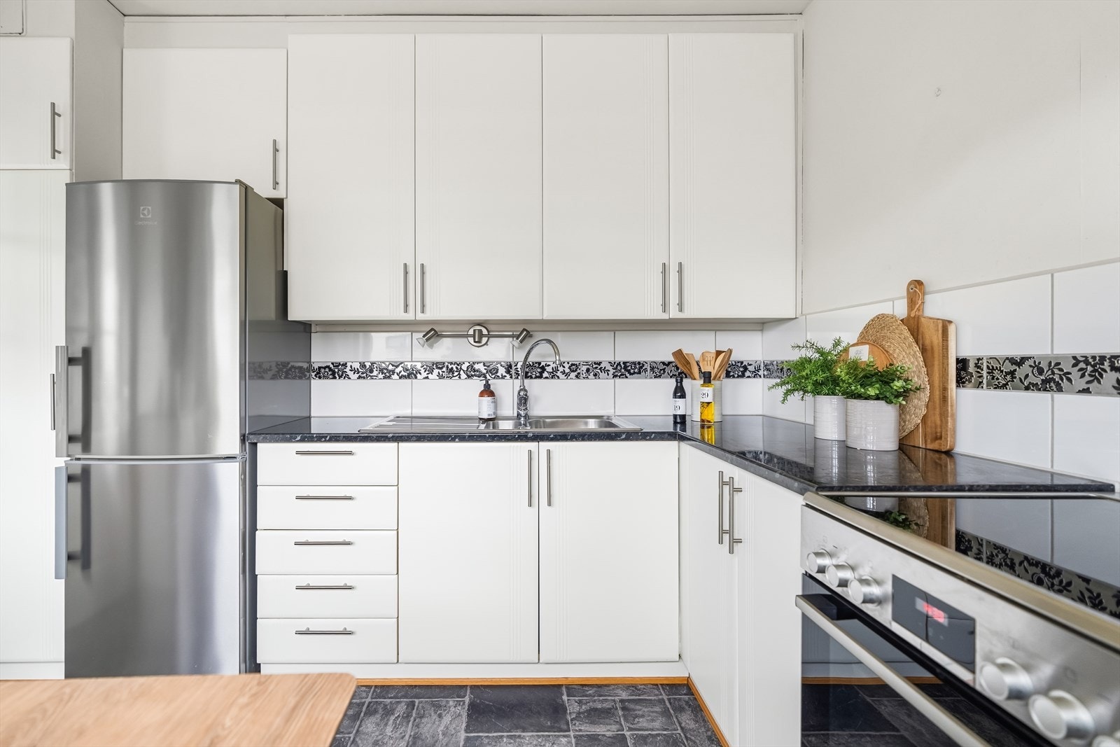 Den stilrene kjøkkeninnredningen har glatte grå fronter og laminat benkeplate med nedfelt kum i rustfritt stål Galleribilde