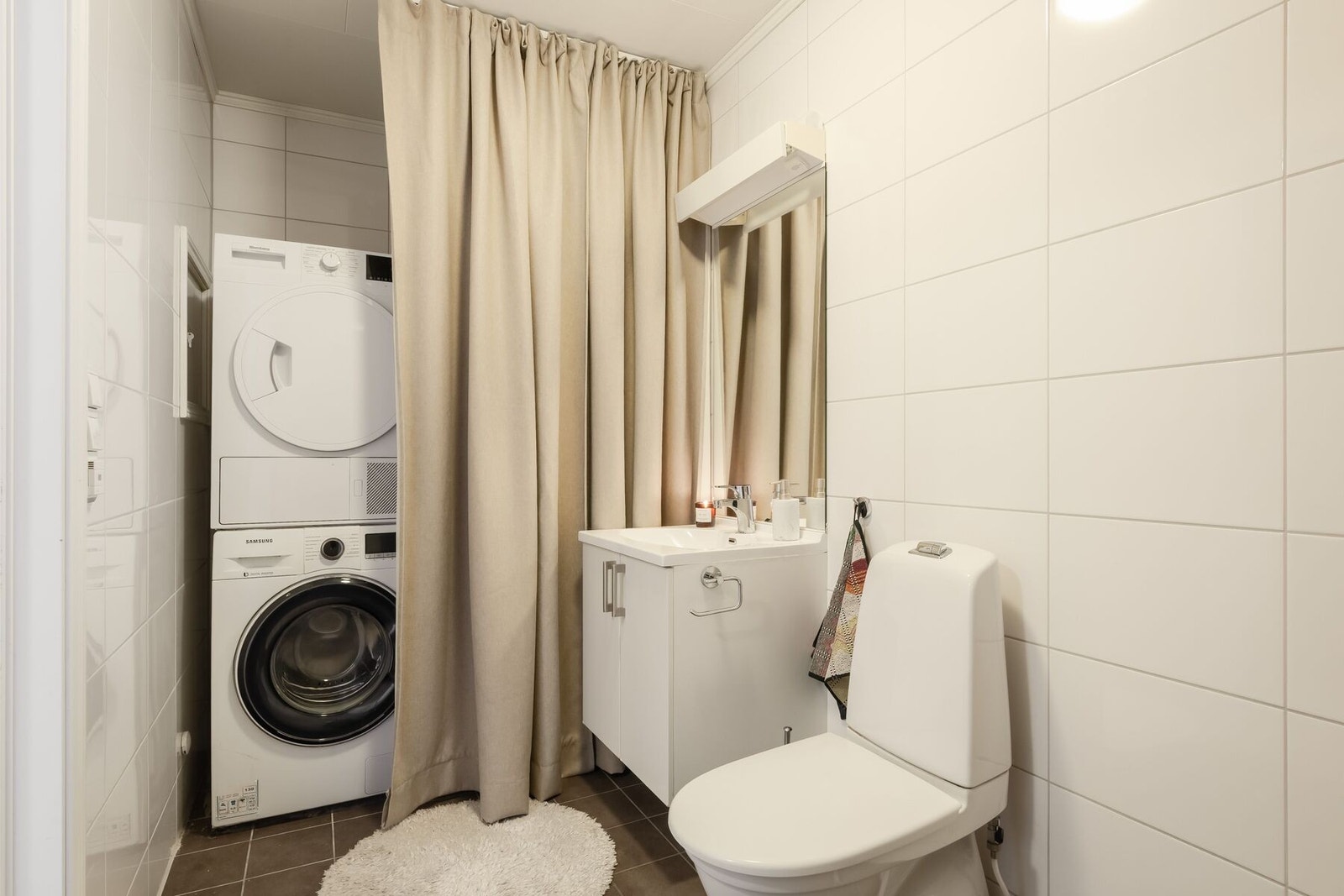Badet er praktisk innredet med dusjnisje, servantinnredning, vegghengt toalett og opplegg for vaskemaskin. Galleribilde