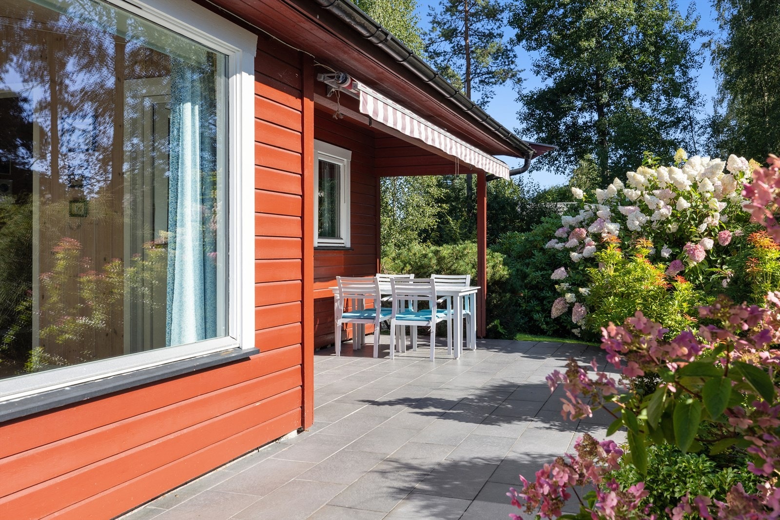 Den frodige og velstelte beplantningen rundt terrassen skaper en lun og skjermet atmosfære, samtidig som den tilfører farge og liv til området. Galleribilde