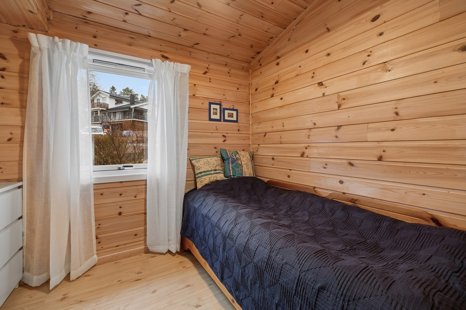 Soverom 2 er et lunt og innbydende rom med enkeltseng og samme gjennomgående trepanel som gir en helhetlig stil i boligen. Galleribilde