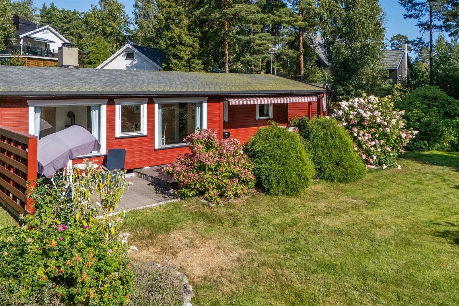 Boligen ligger lunt og solrikt til på en romslig tomt, pent opparbeidet med gressplen, prydbusker, naturtomt og fjell i dagen. Galleribilde