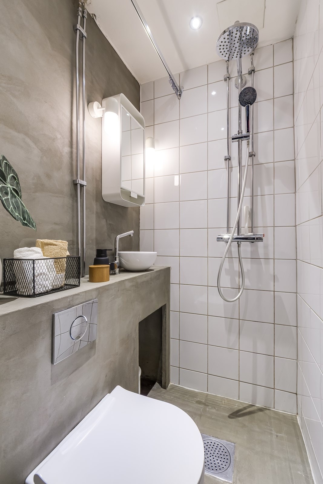 Badet er utstyrt med en praktisk dusjløsning med forheng, vegghengt toalett og et speilskap med oppbevaringsplass. Galleribilde