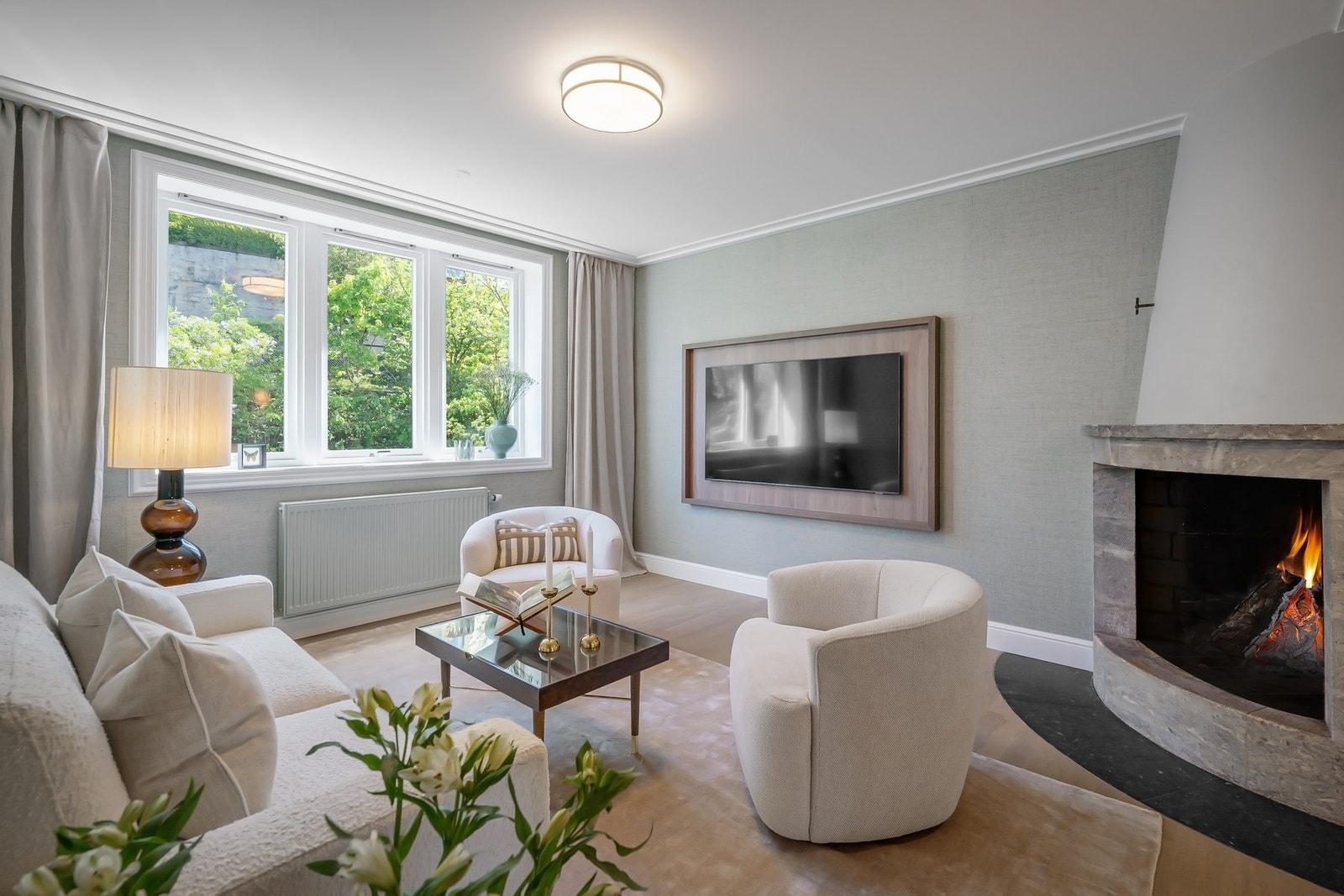TV-stue med åpen peis, generøs takhøyde og skreddersydd ramme som integrerer TV-en på elegant vis. Galleribilde