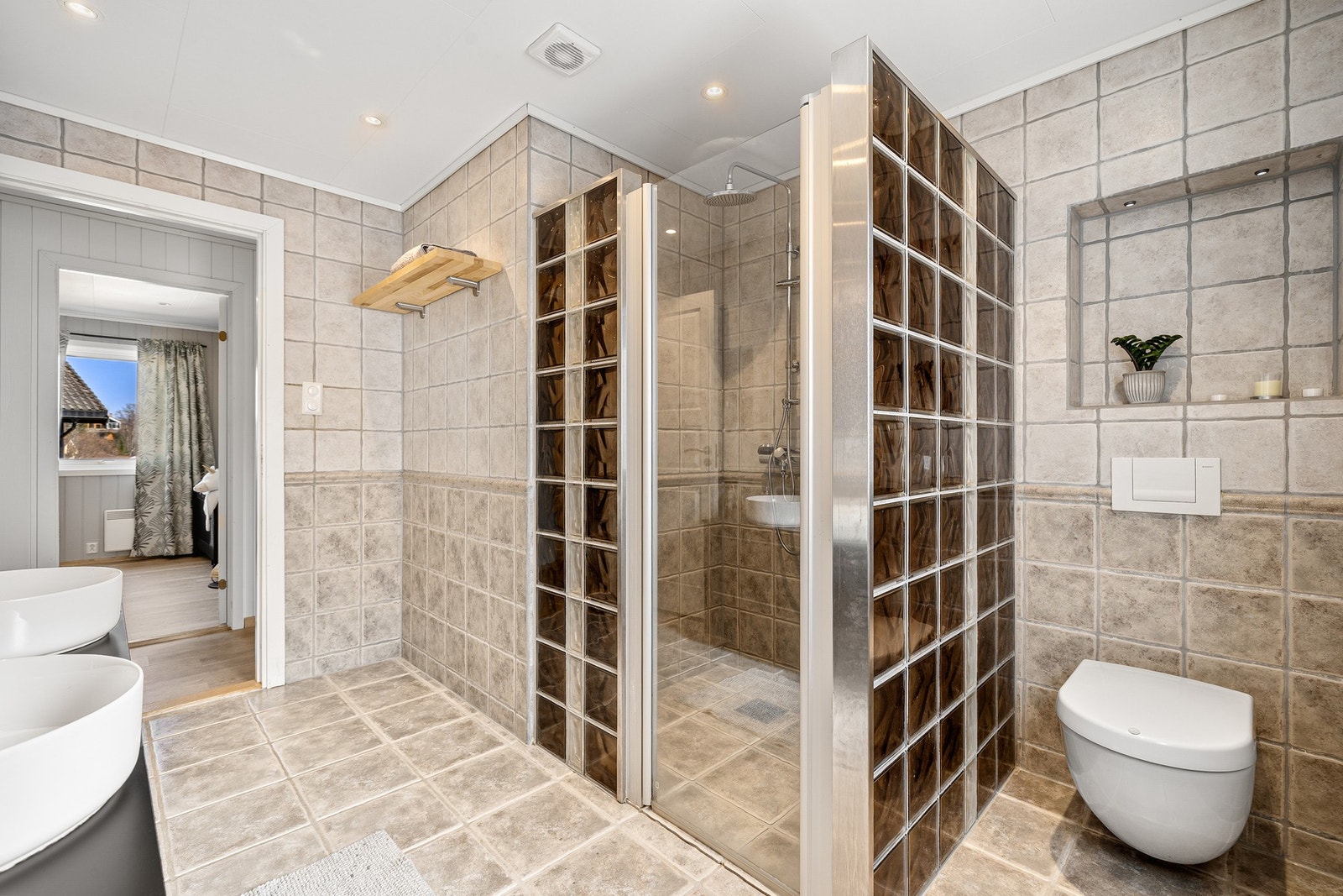 Badet er innredet med dobbel servant, toalett og en stor dusjnisje. Galleribilde