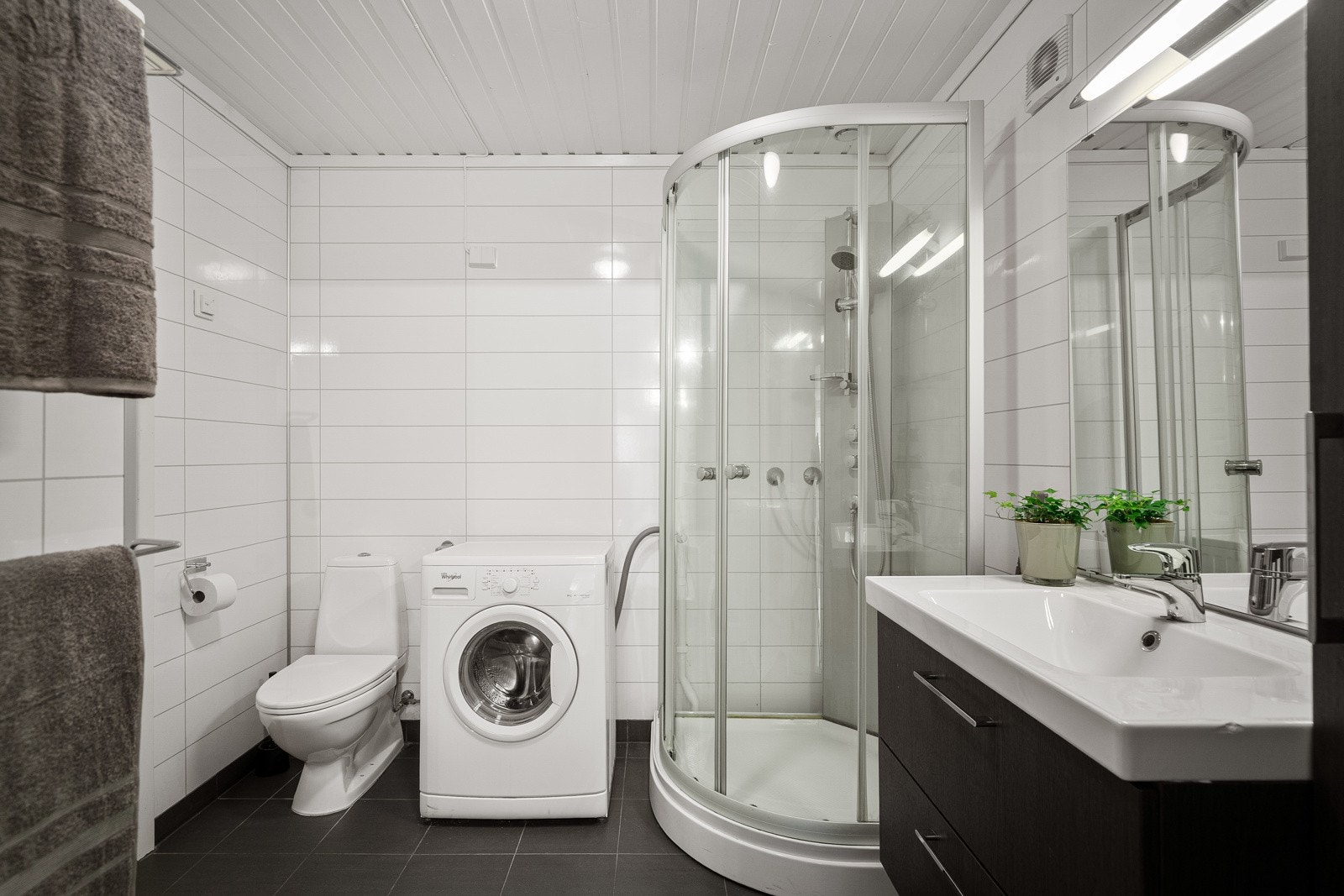 Badet er lekkert og innredet med dusjkabinett, servant med skuffer, toalett og opplegg til vaskemaskin Galleribilde