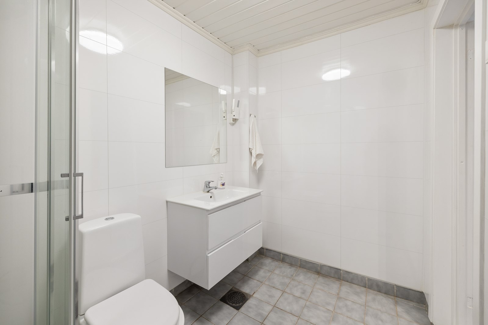 Badet har flislagt gulv og baderomsplater på vegger. Galleribilde
