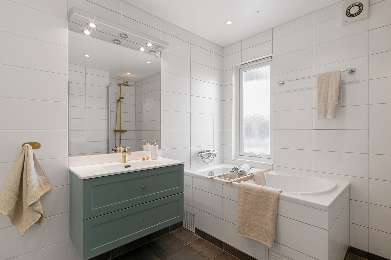 Planløsningen byr på et bad i første etasje og et eget vaskerom i underetasjen. Badet har mørke gulvfliser med varmekabler kombinert med lyse veggfliser. Galleribilde