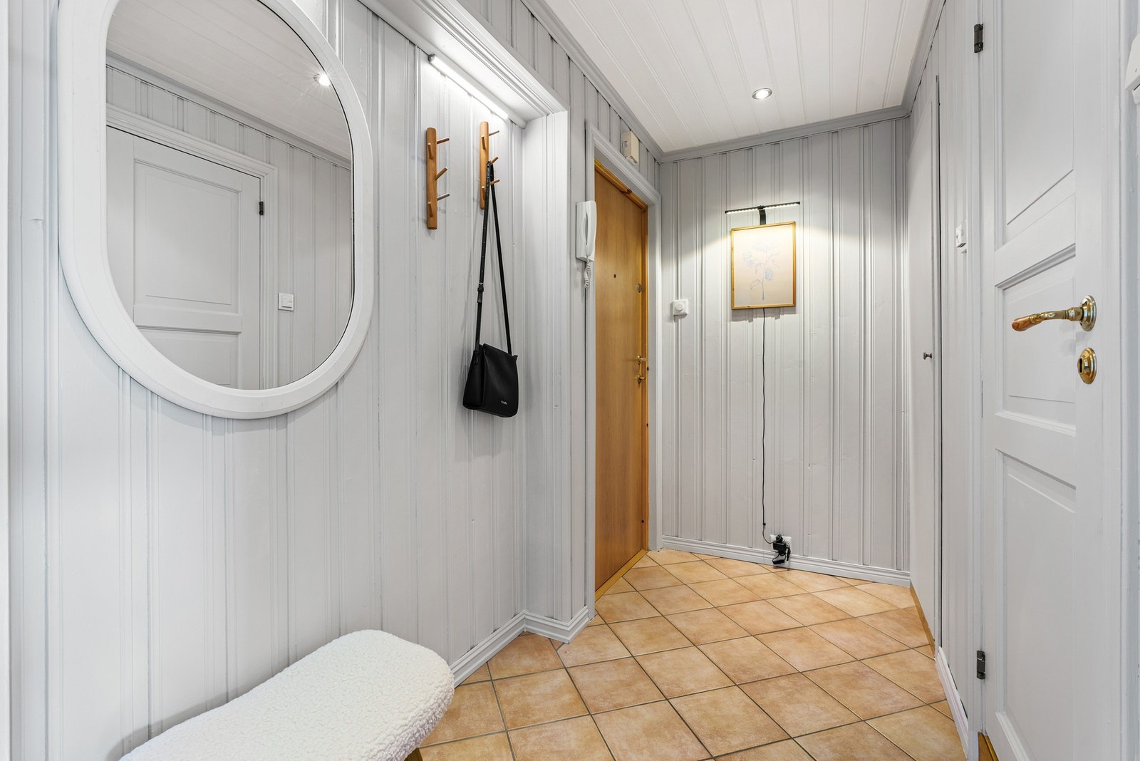 Lys entré med malte vegger, downlights i himlingen og fliser på gulv. Galleribilde