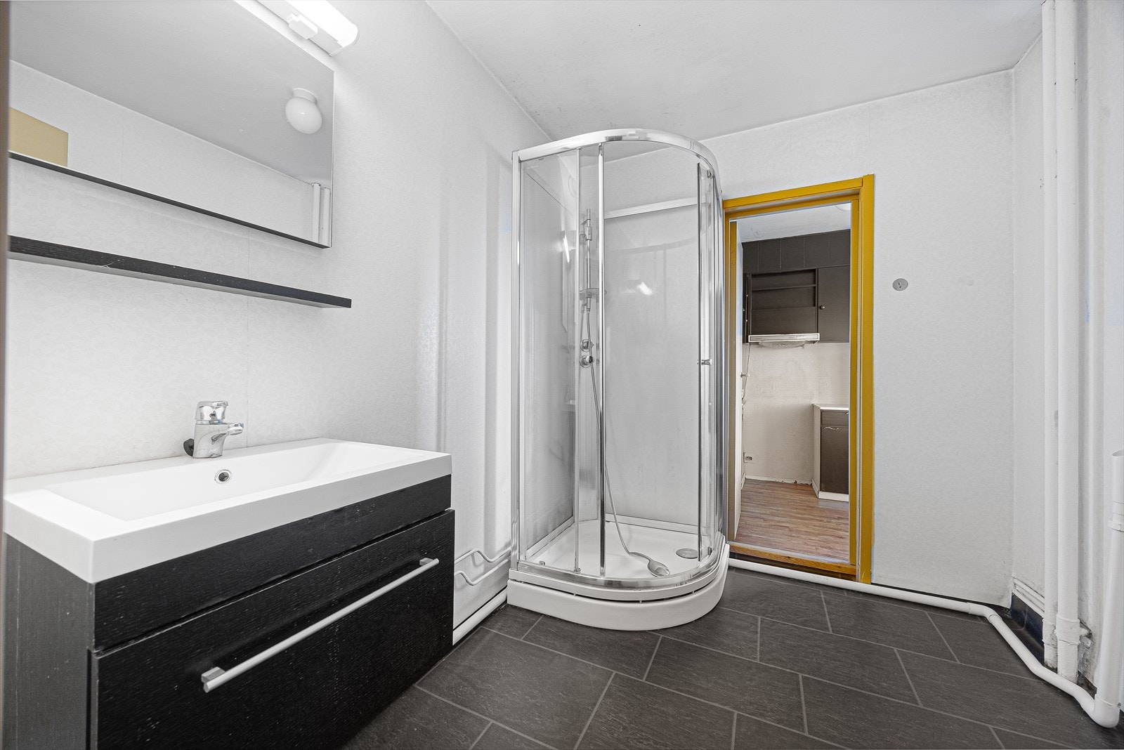 Badet er innredet med dusjkabinett, servantinnredning og opplegg for vaskemaskin. Galleribilde