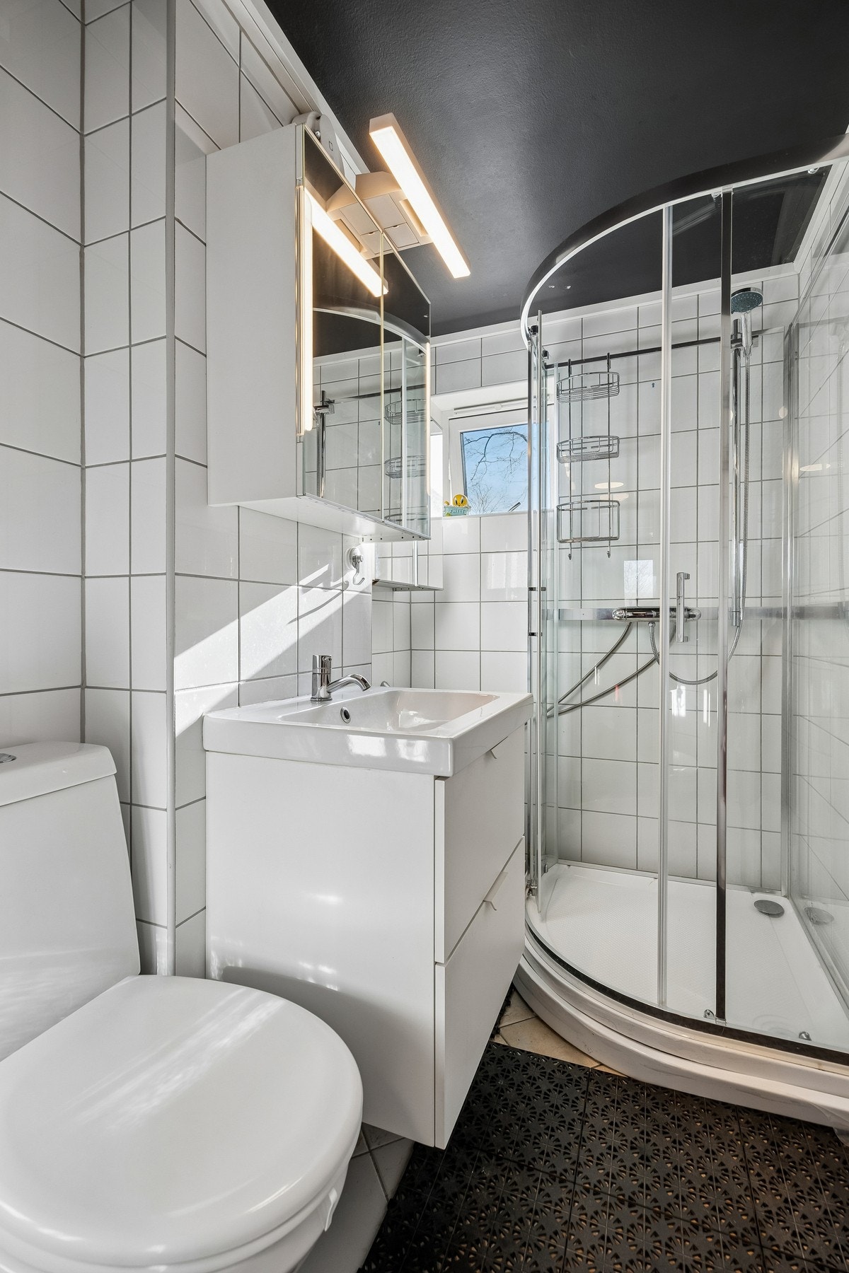 Badet er utstyrt med dusjkabinett, og oppleves som tidløst med flisvalg og glatte innredningsfronter. Galleribilde