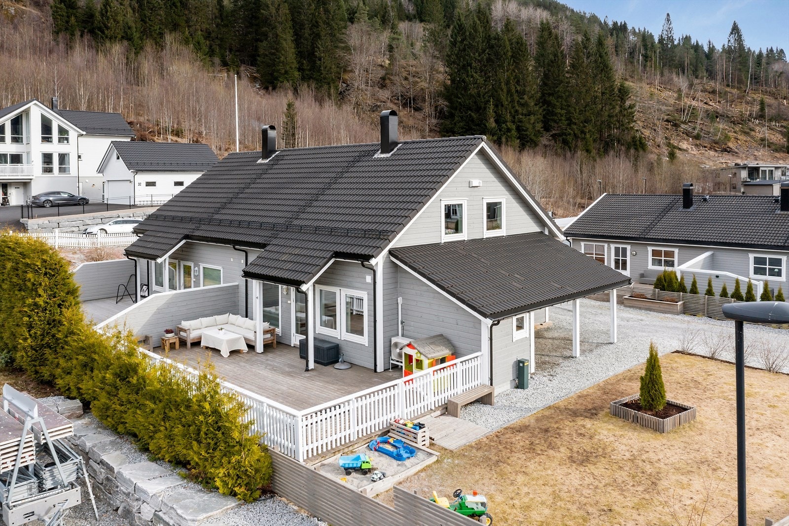 Vestvendt del av tomannsbustad med stor terrasse og stor flat hage Galleribilde