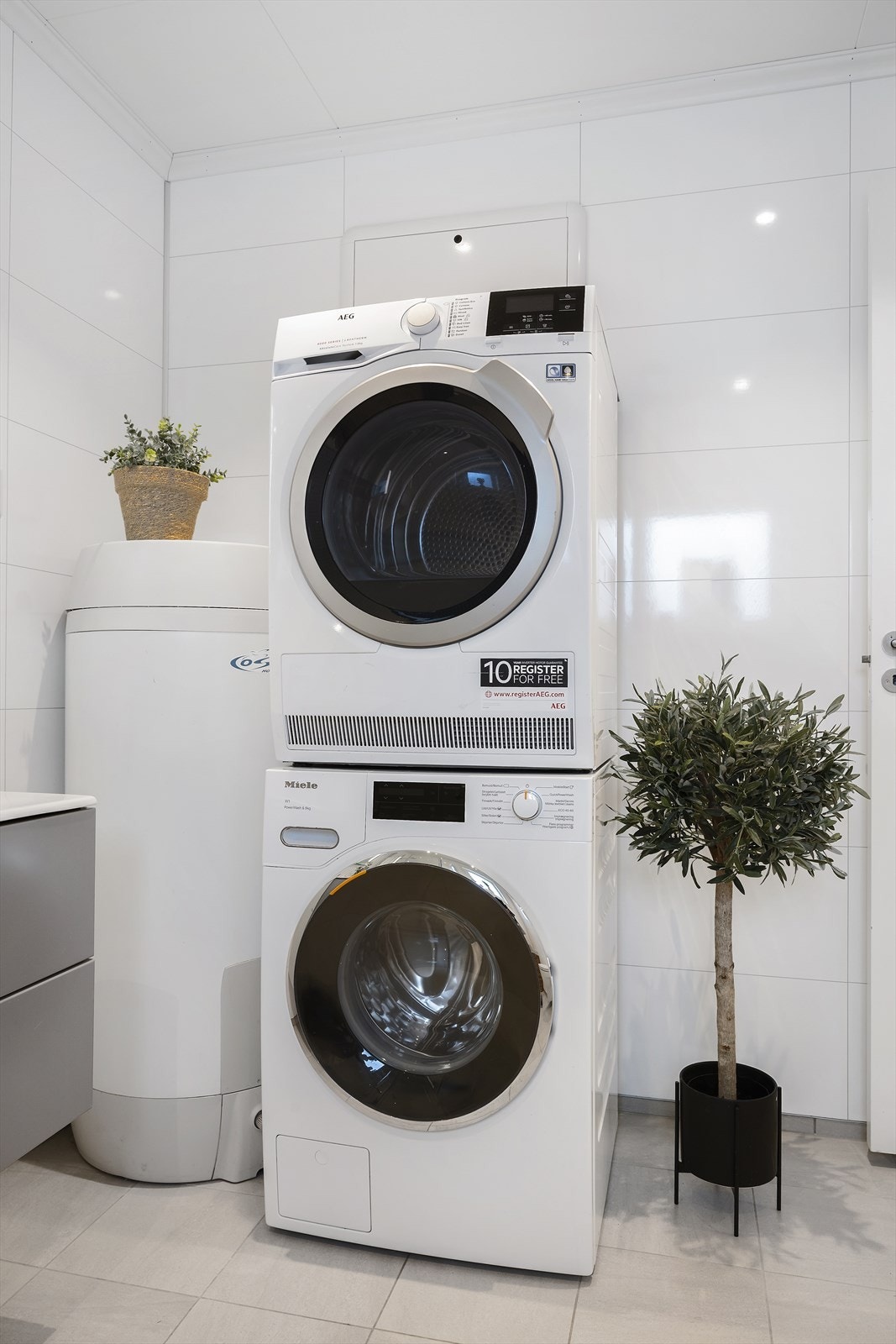Badet er kombinert vaskerom med praktisk opplegg for vaskemaskin og plass til tørketrommel Galleribilde