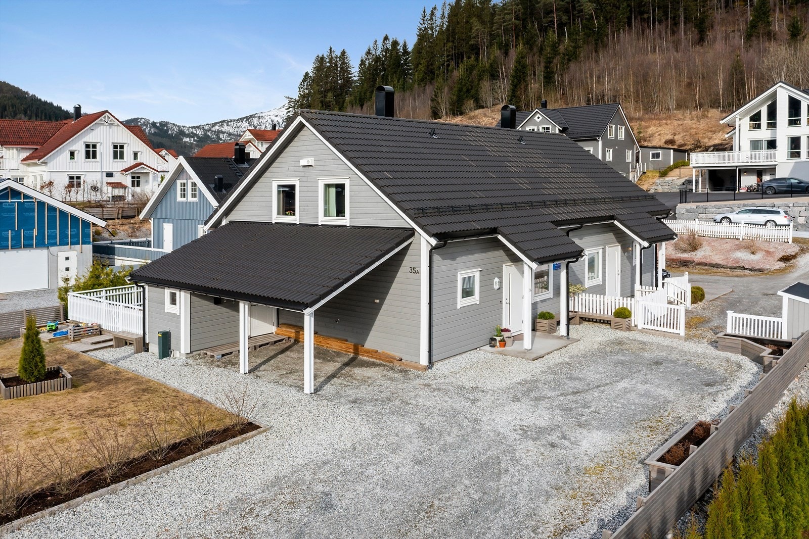 Stort gruslagt tun og integrert carport med el-bil ladar og sportsbod. Eit praktisk og innbydande inngangsparti. Galleribilde