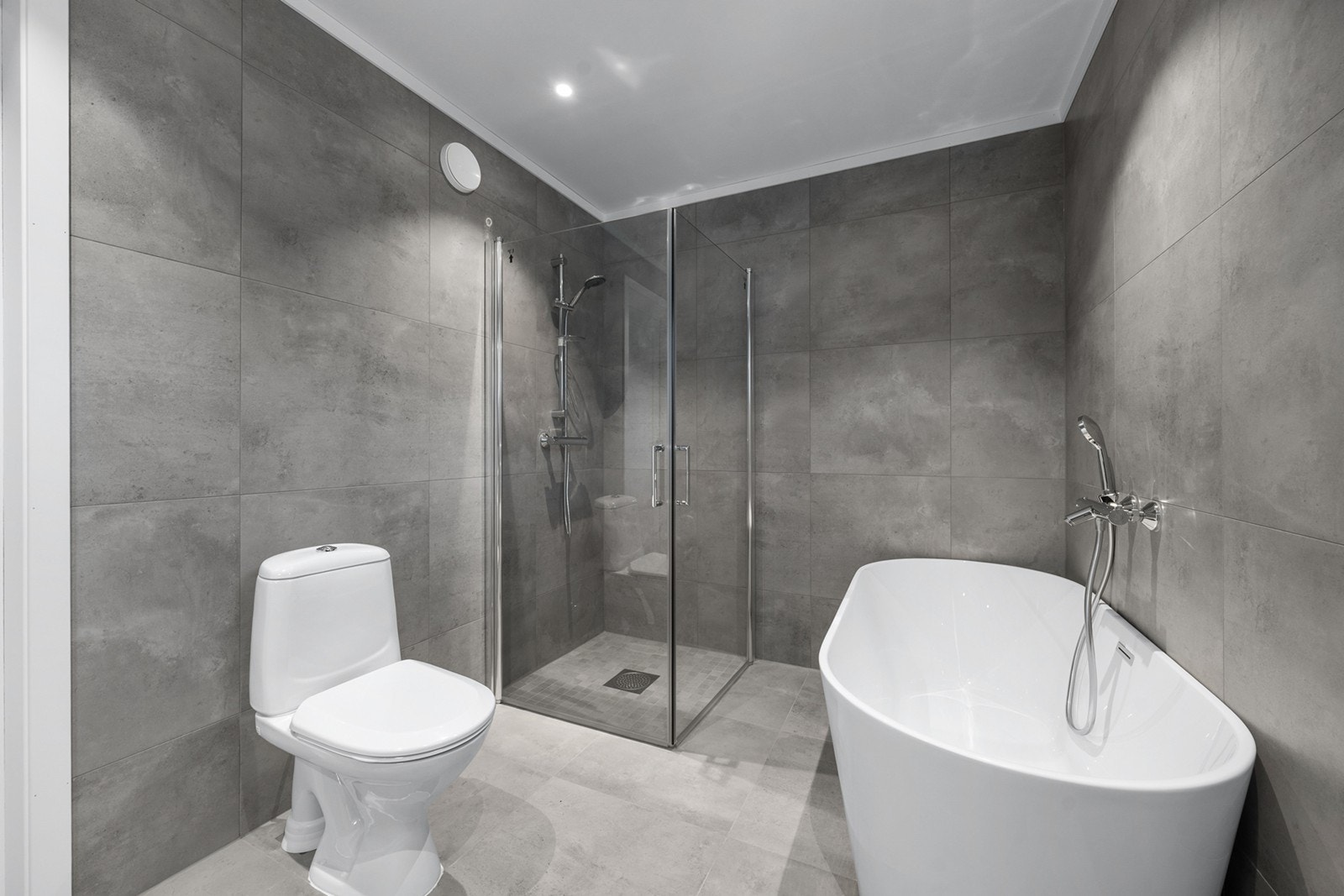 Delikat og romslig bad med flislagte overflater på gulv og vegger. Badet er innredet med badekar, dusjnisje med glassvegger. Galleribilde