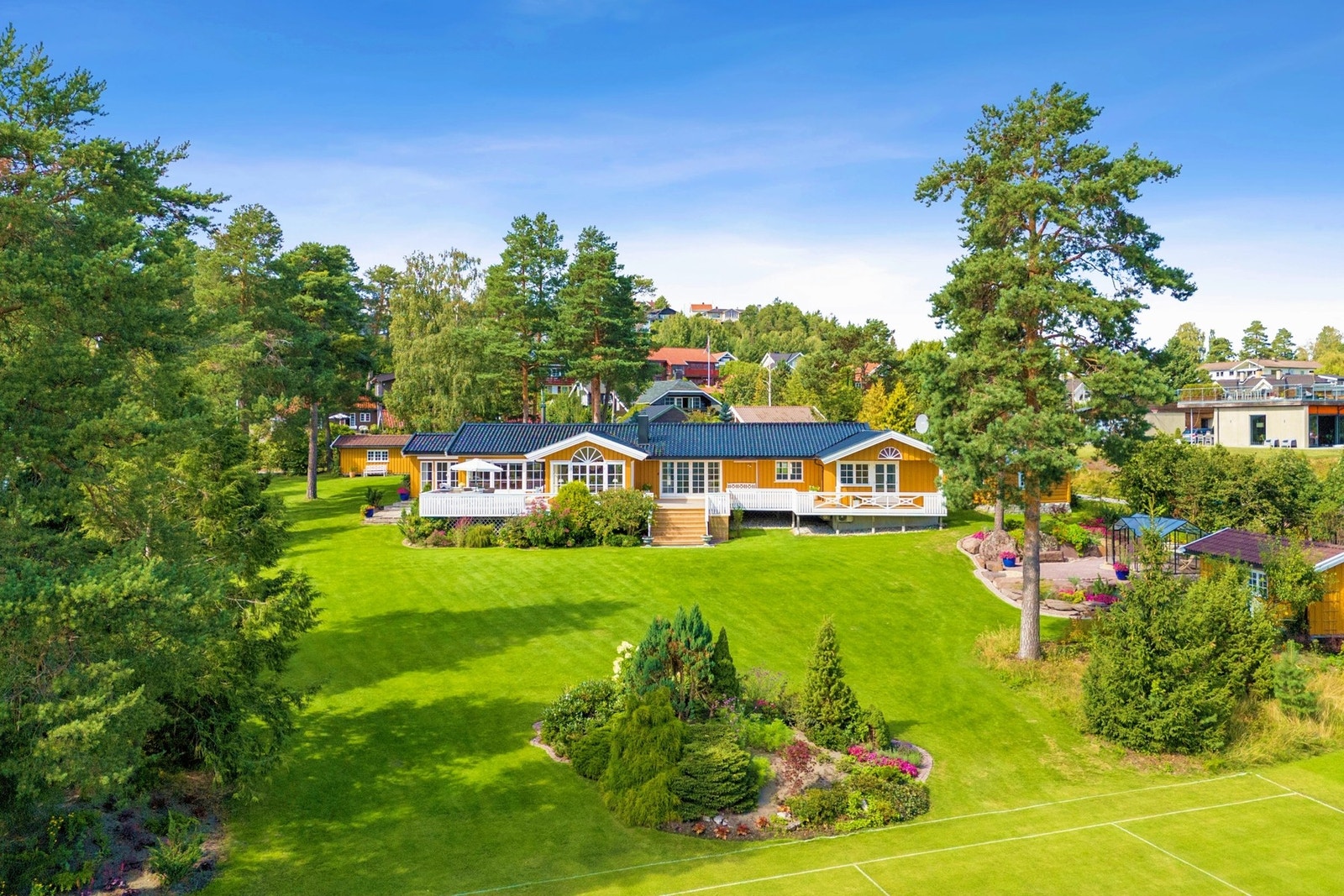 En praktfull, parkmessig opparbeidet hage med frodige blomsterbed og generøse plenarealer. Galleribilde