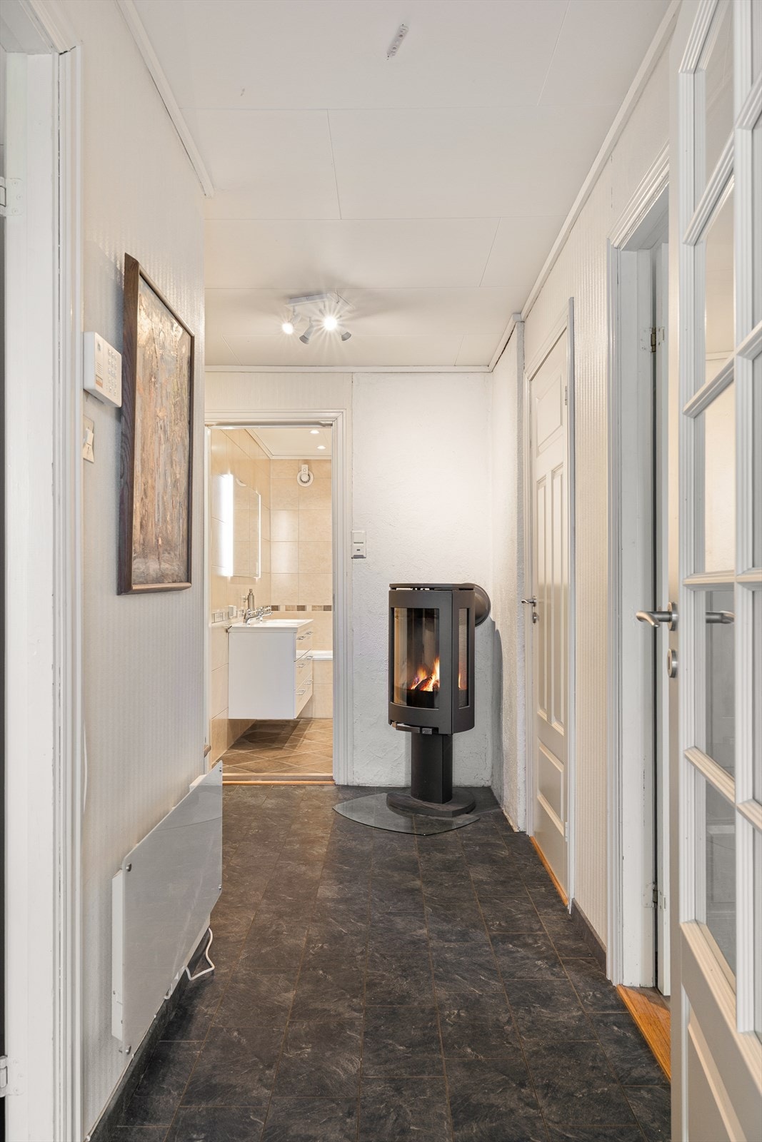 Gang/entrè ned på bakkeplan. Her er det også montert vedovn, som på kalde høst og vinterdager kan hjelpe varme om boligen om ønskelig. Galleribilde