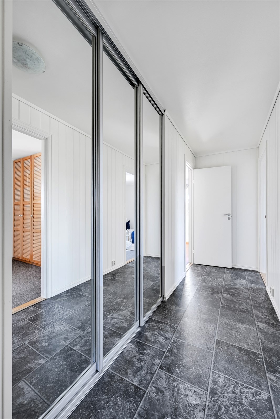 Gangen i hovedetasjen har en romslig skyvedørsgarderobe med speilfronter. Galleribilde
