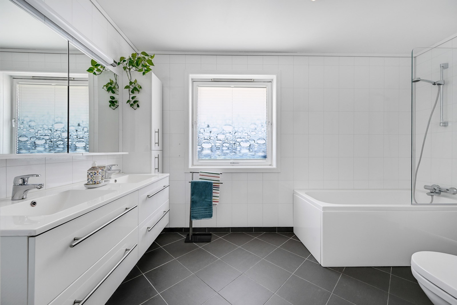 Rommet er innredet med badekar og vegghengt toalett, og har vegger med laminerte baderomsplater. Galleribilde