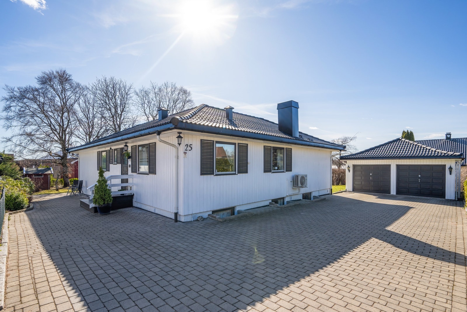 Belegningsstein på gårdsplassen og innkjørselen fører til en frittliggende dobbelgarasje på 45 m², bygget i 1990. Galleribilde