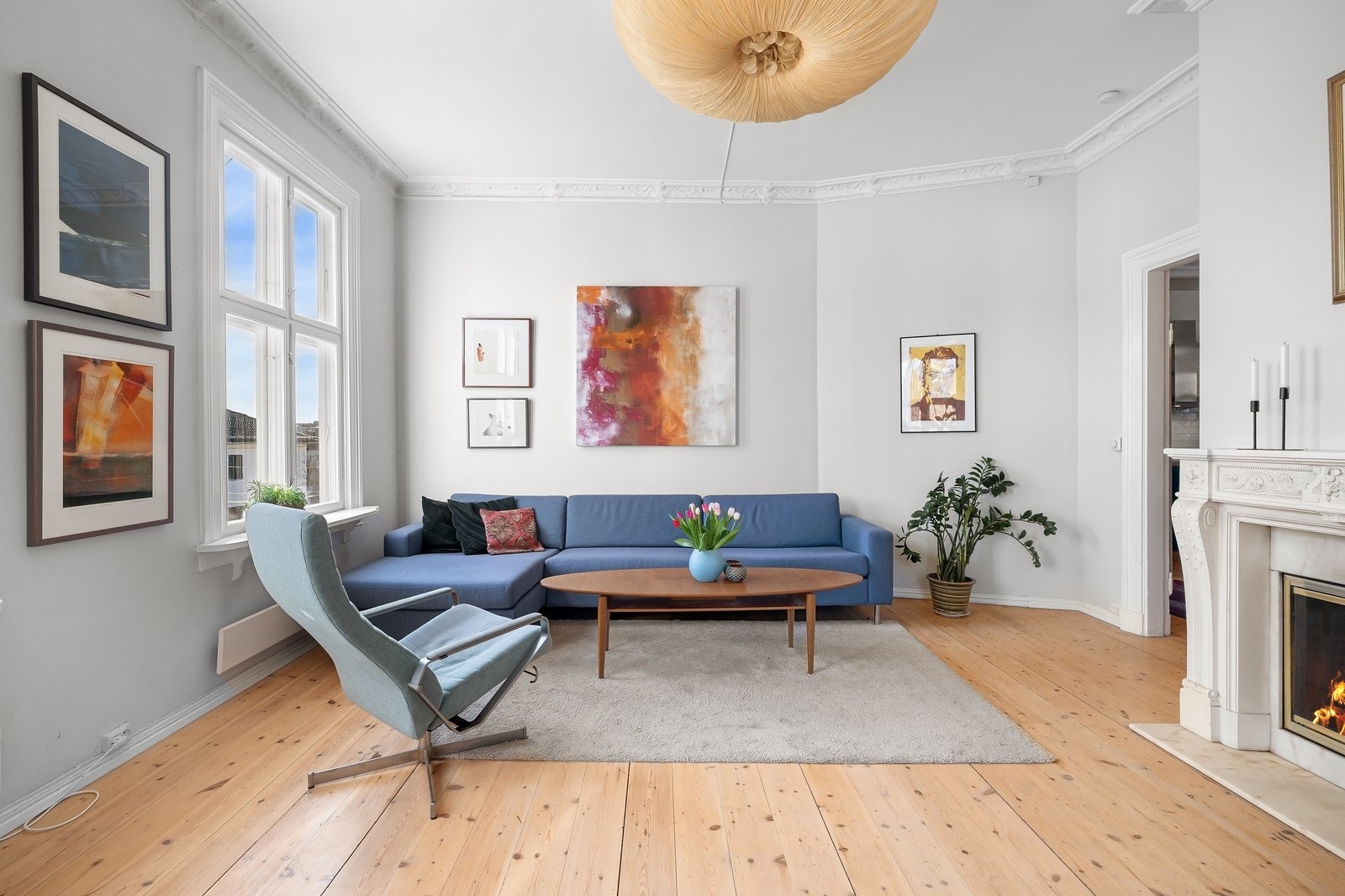 Her har man en åpen stueløsning med peis og gjennomgående stukkaturdetaljer Galleribilde