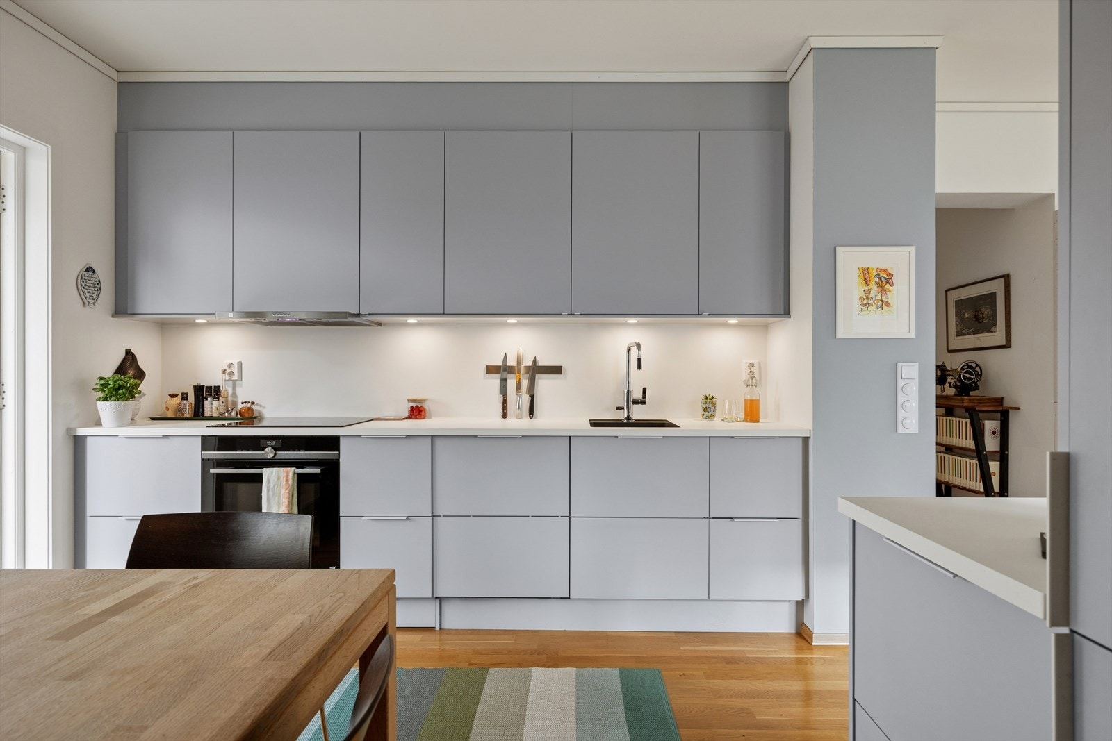 Smakfull innredning med grå, glatte fronter og laminat benkeplate. Benkeplaten er utstyrt med underlimt oppvaskkum og ettgreps blandebatteri med uttrekkbar dusjfunksjon. Galleribilde